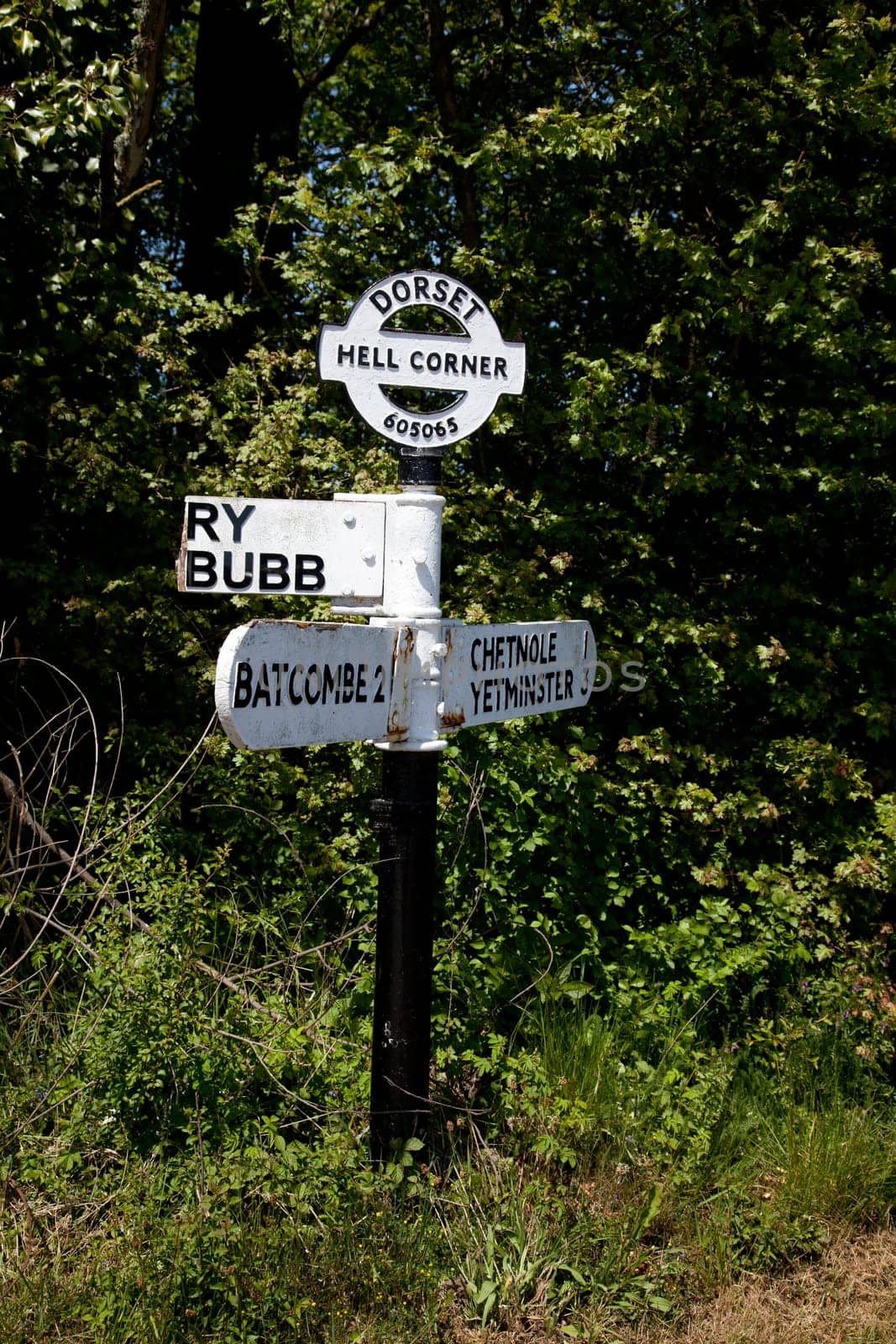 An old-fashioned black and white wooden road signpost at the unusually named Hell corner in the county of Dorset in England