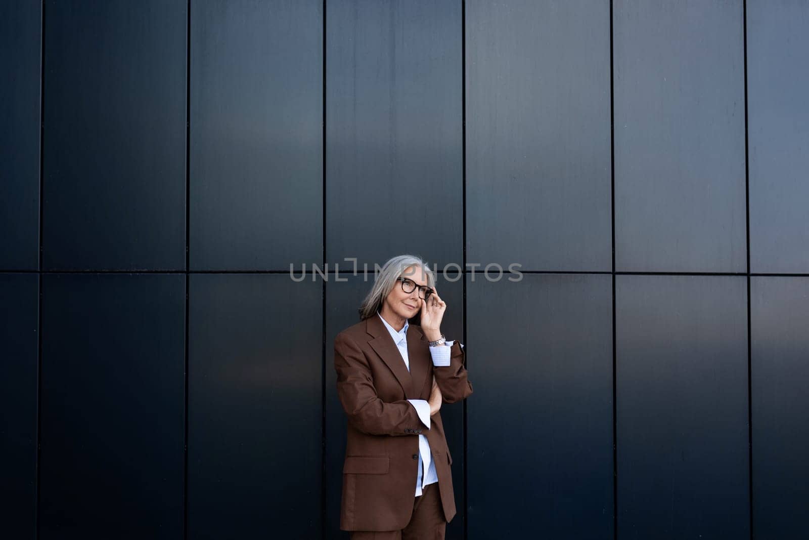 portrait of a well-groomed gray-haired middle-aged woman with a bob hairstyle dressed in a jacket and trousers. middle aged business concept by TRMK