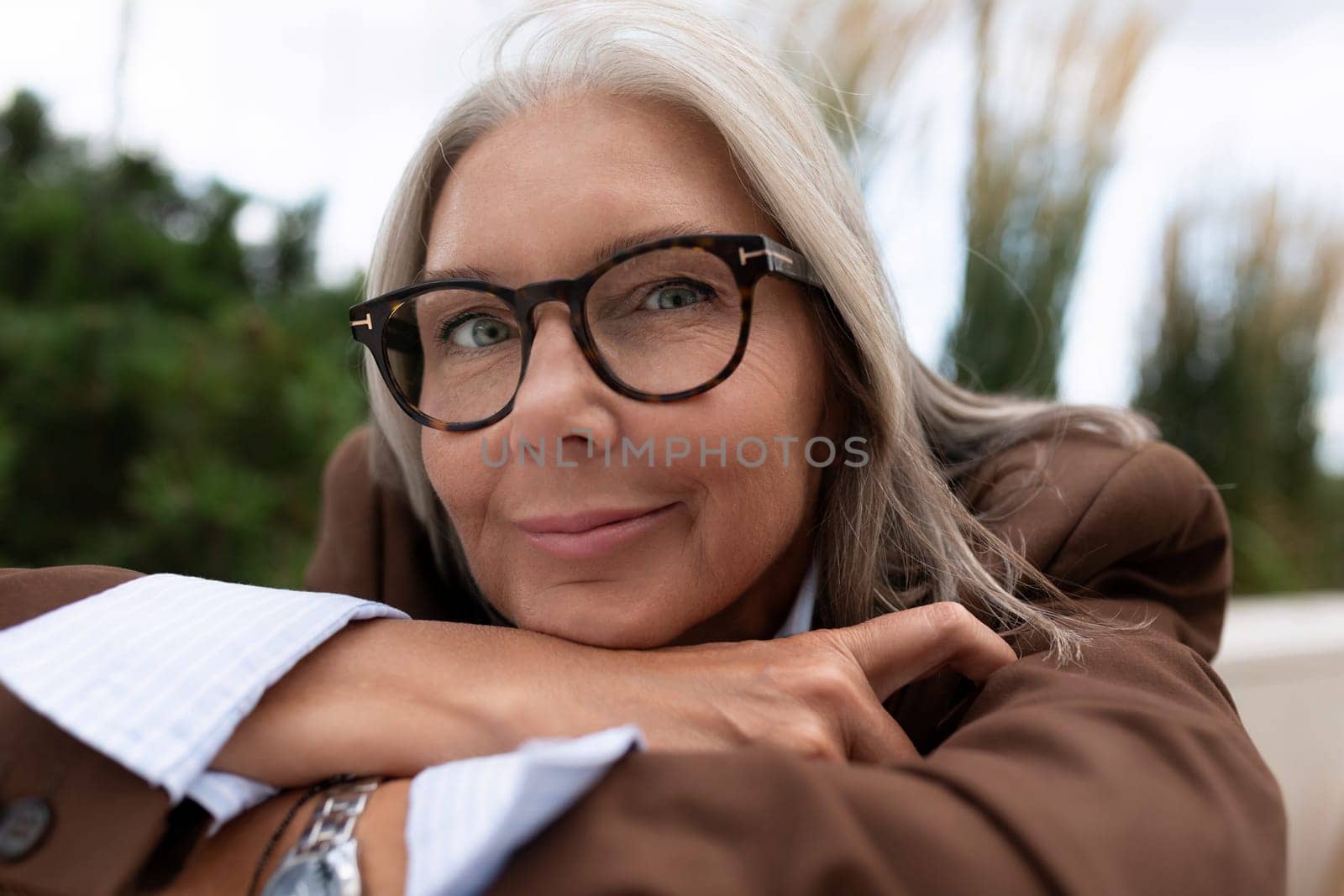 well-groomed charming entrepreneur woman of mature years enjoys the weather sitting on the street.