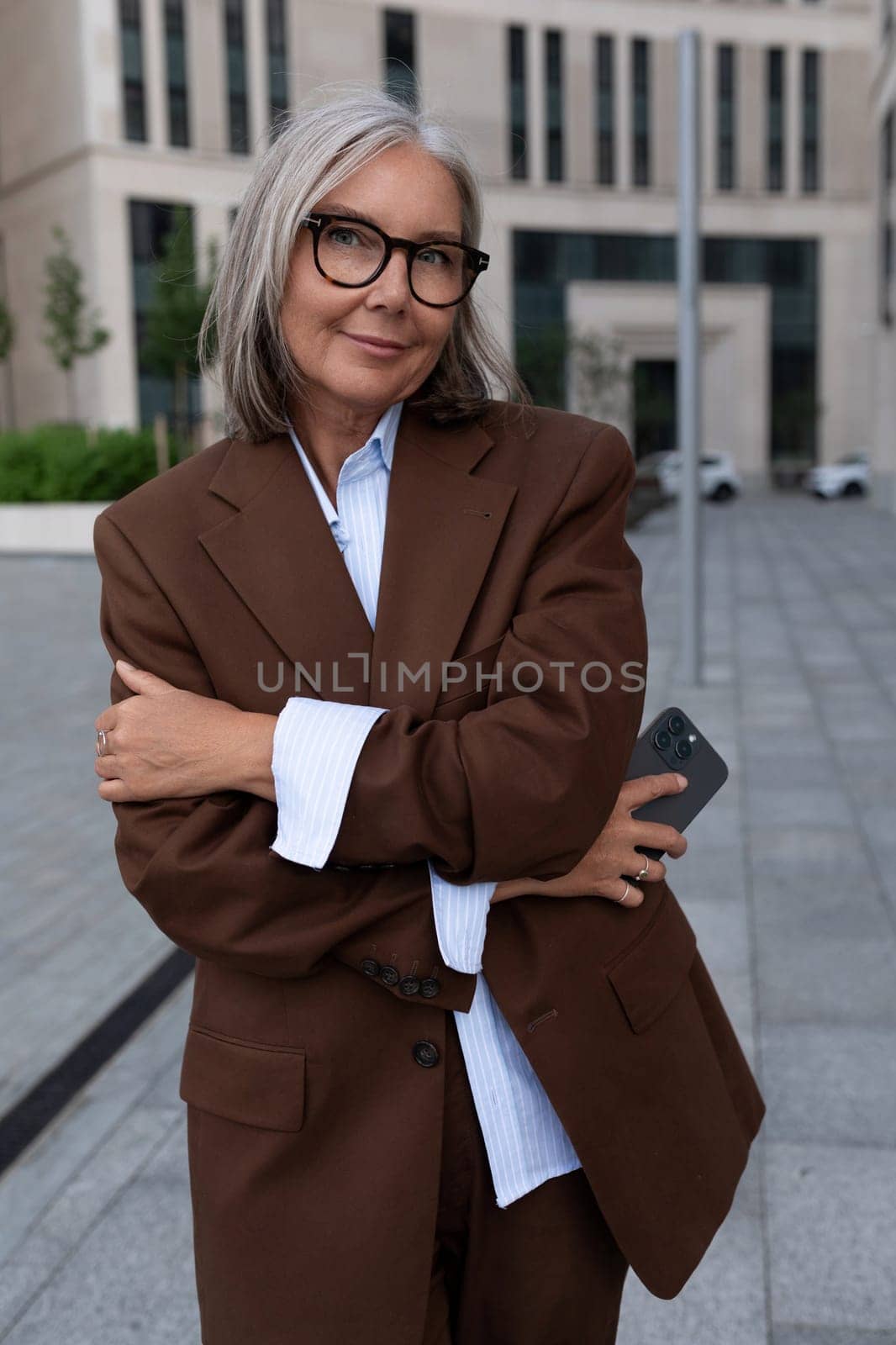 charming mature woman with gray hair in a stylish suit walks around the city.