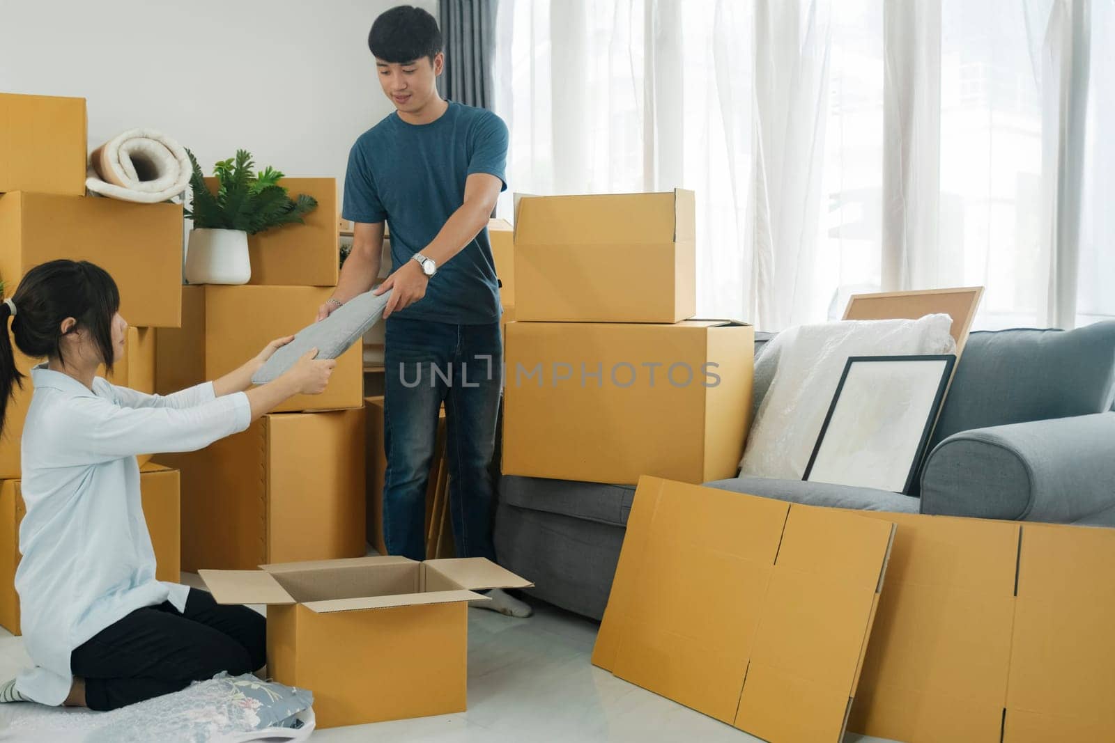 Young married couple moving into new home. They're unpacking or packing card boxes with their accessories.