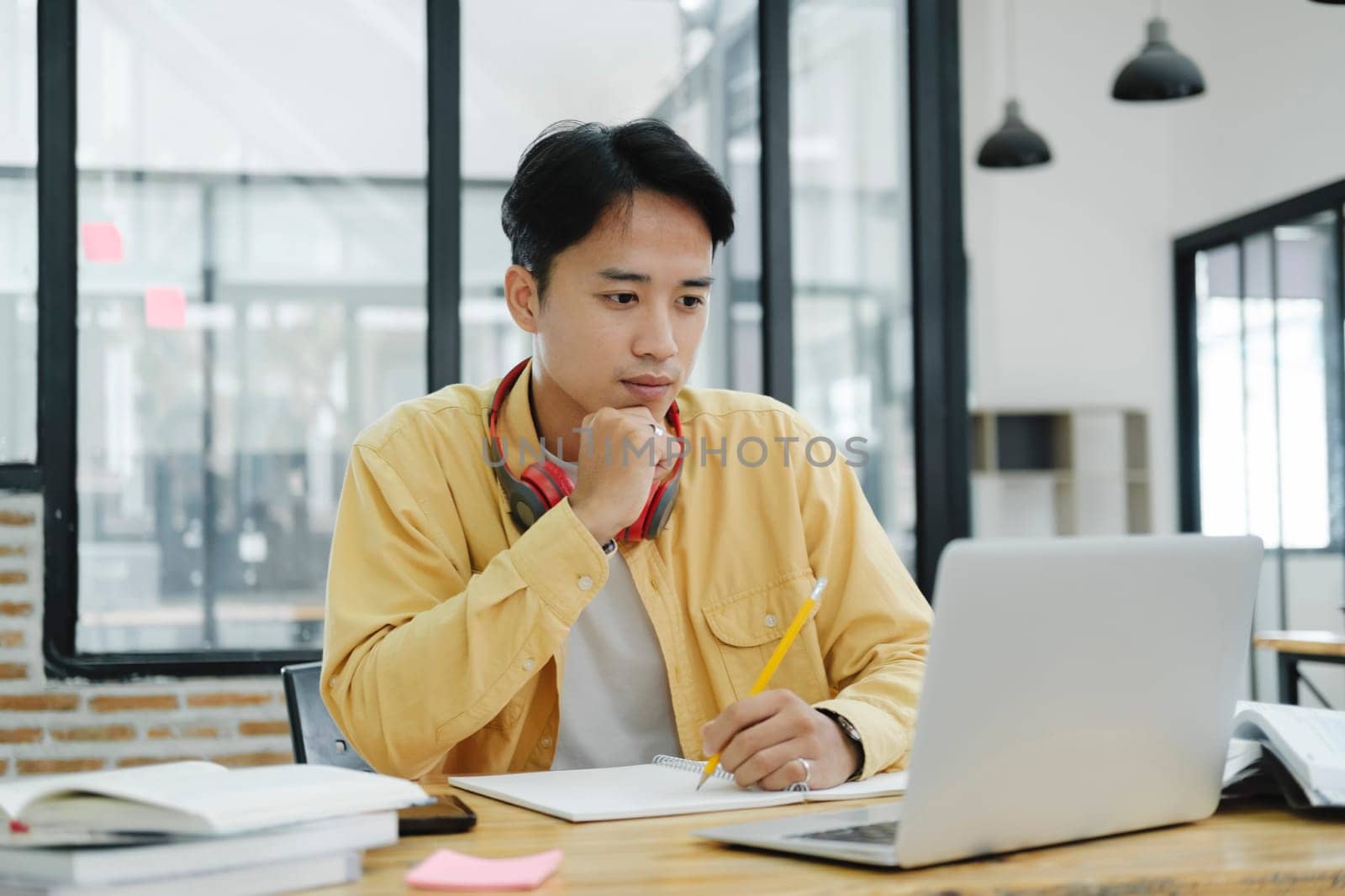 Online education, e-learning. Young collage student using computer and mobile device studying online. Asian young student online learning class study online video call zoom teacher.