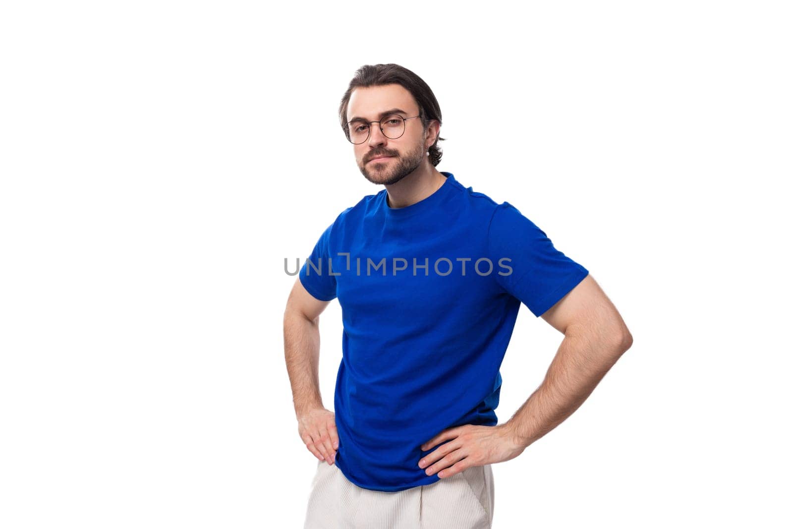 young surprised confident caucasian brunette man with a beard and glasses in a blue t-shirt on a white background.