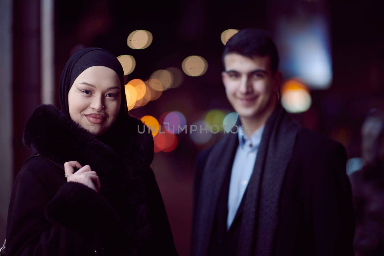 Happy multicultural business couple walking together outdoors in an urban city street at night near a jewelry shopping store window. by dotshock