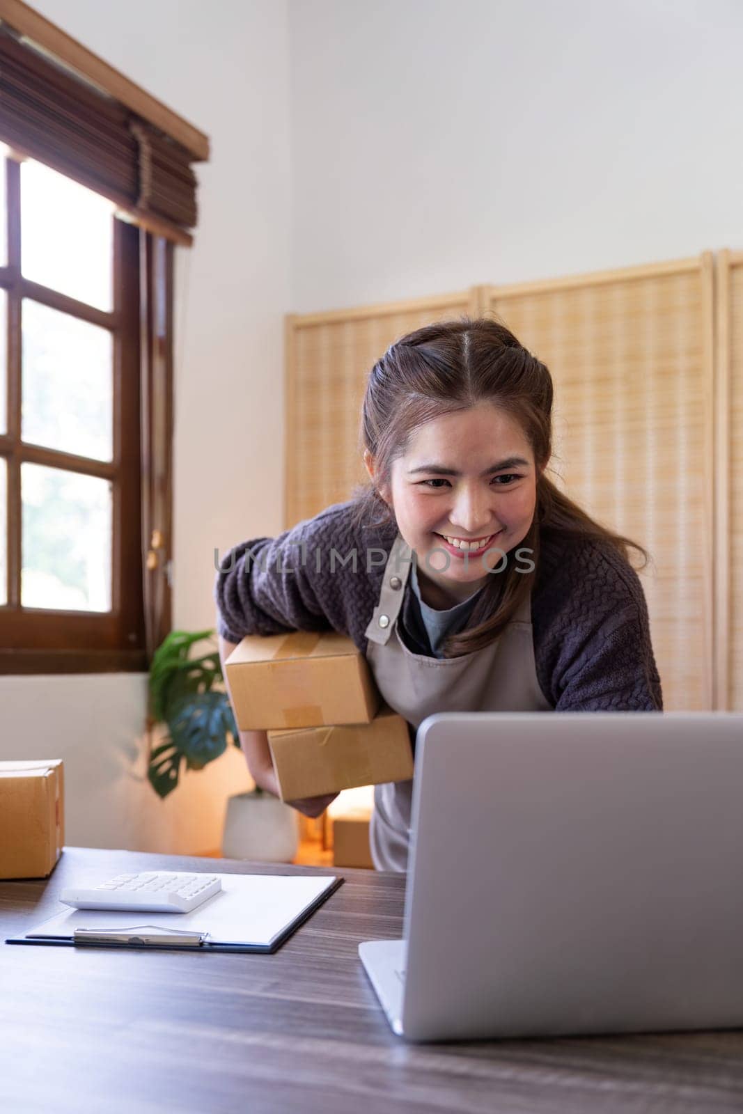 Startup SME small business entrepreneur of freelance Asian woman using laptop and box to receive and review order online to prepare to pack sell to customers, online sme business ideas by nateemee