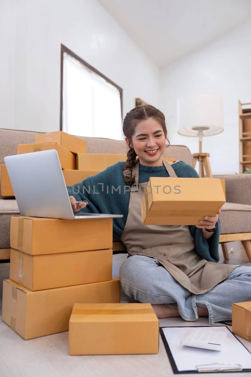 Young woman working online ecommerce shopping at her shop. Young woman seller prepare parcel box of product for deliver to customer. Online selling, ecommerce. Selling products online by nateemee