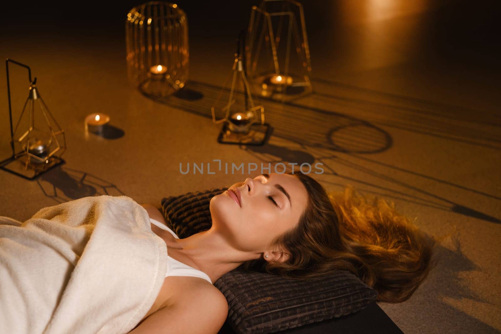 A woman lies on the floor covered with a blanket with her eyes closed and relaxes after a workout , shavasana pose.