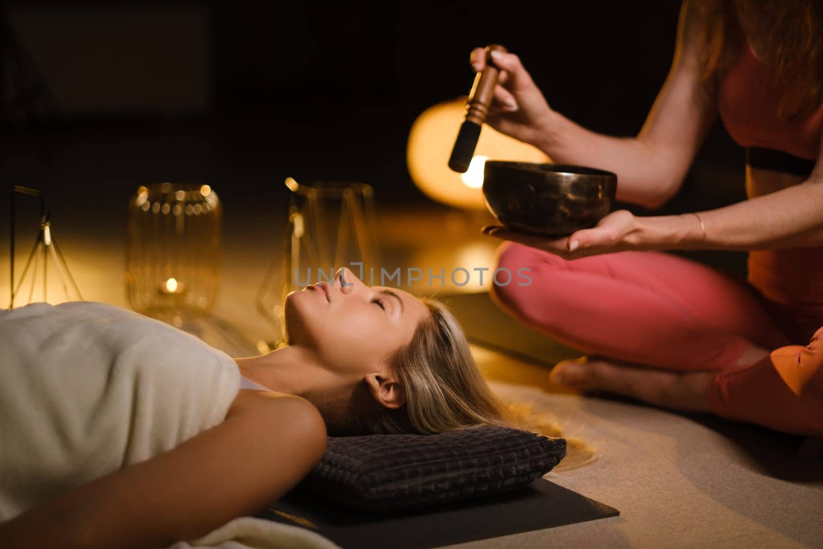 a girl lying on the floor relaxes to the sounds of a Tibetan bowl in the gym.