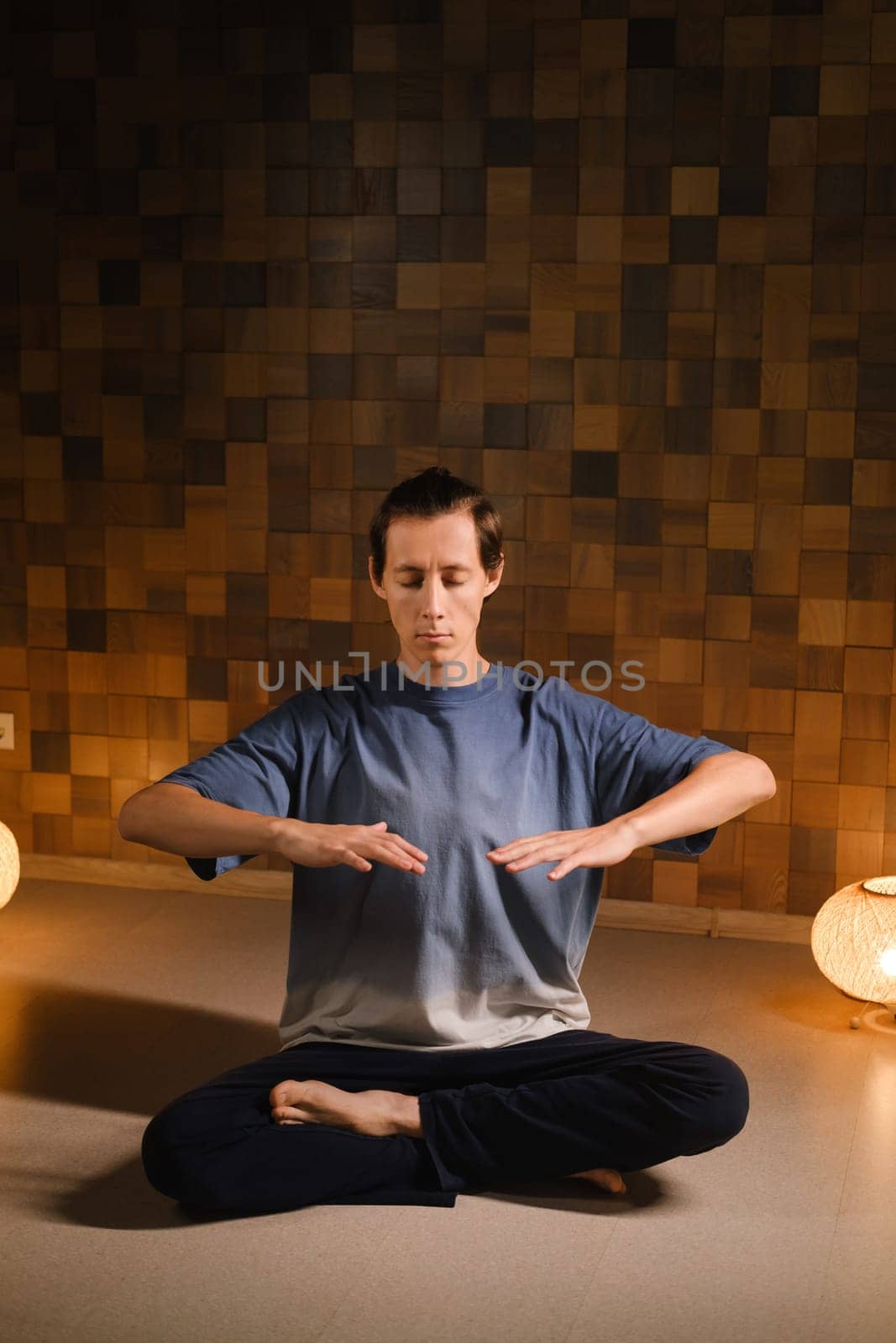 a man in a sports uniform does yoga in a fitness room. the concept of a healthy lifestyle by Lobachad