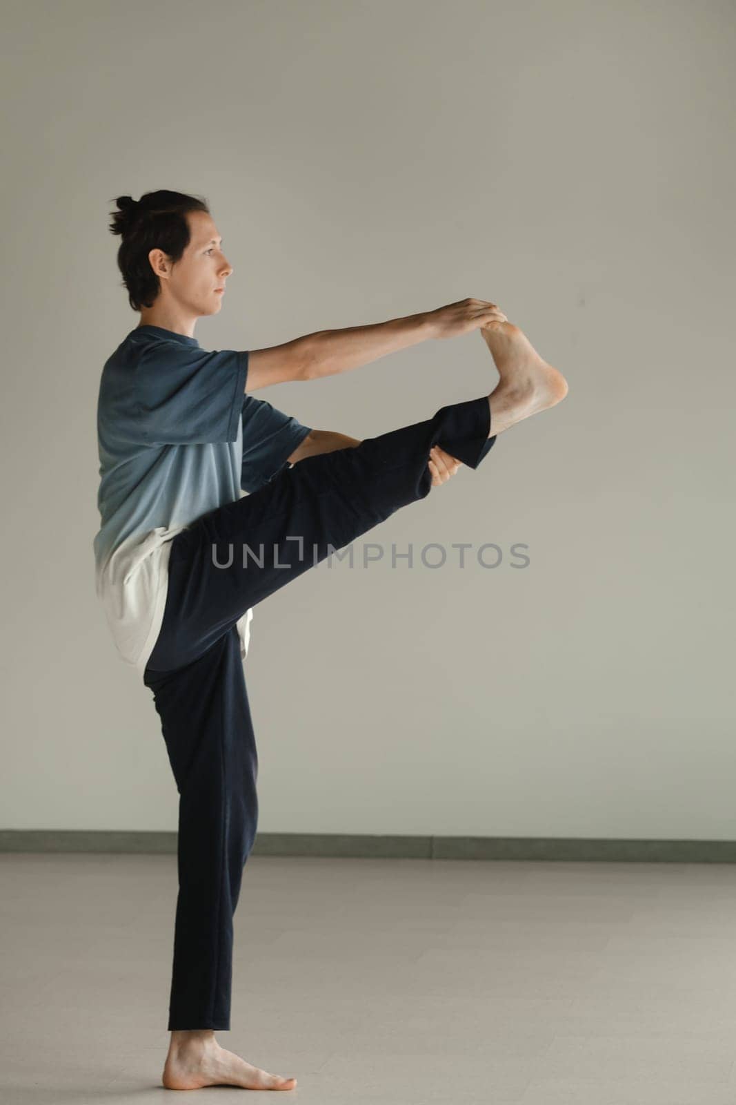 a man in a sports uniform does yoga in a fitness room. the concept of a healthy lifestyle by Lobachad