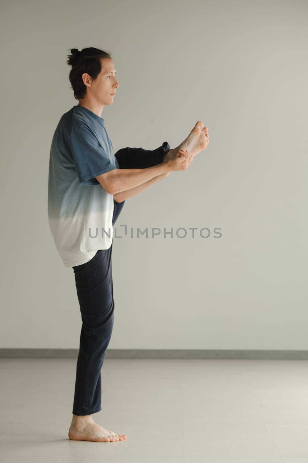 a man in a sports uniform does yoga in a fitness room. the concept of a healthy lifestyle by Lobachad