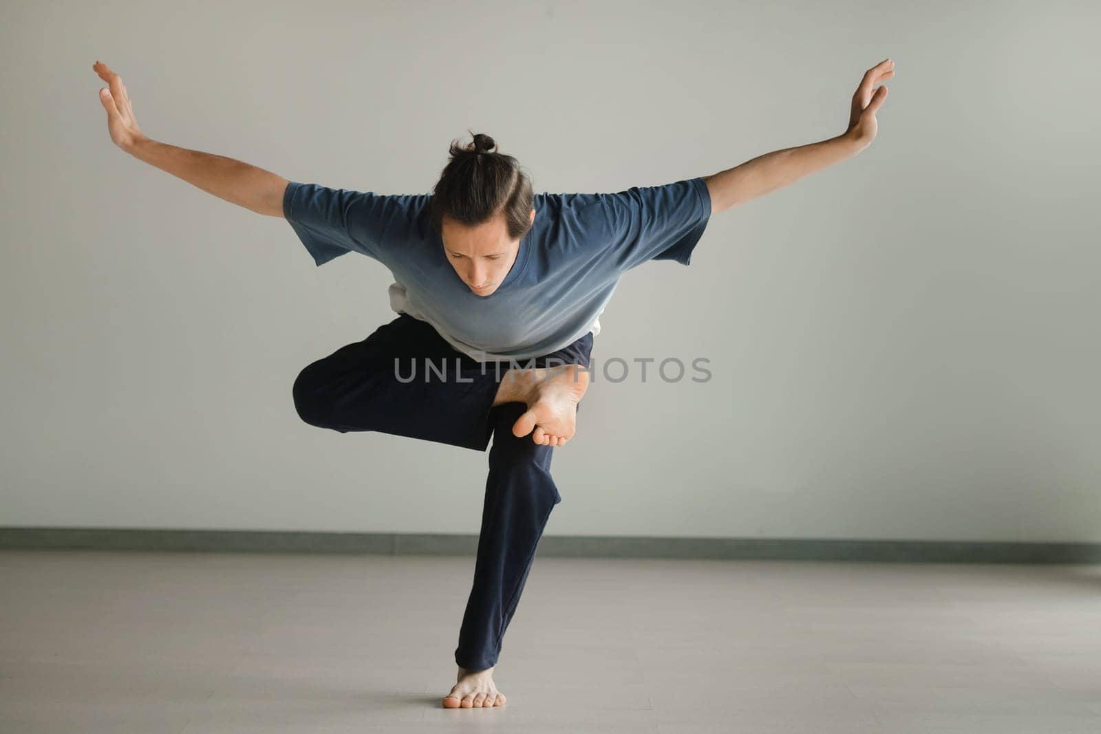 a man in a sports uniform does yoga in a fitness room. the concept of a healthy lifestyle by Lobachad