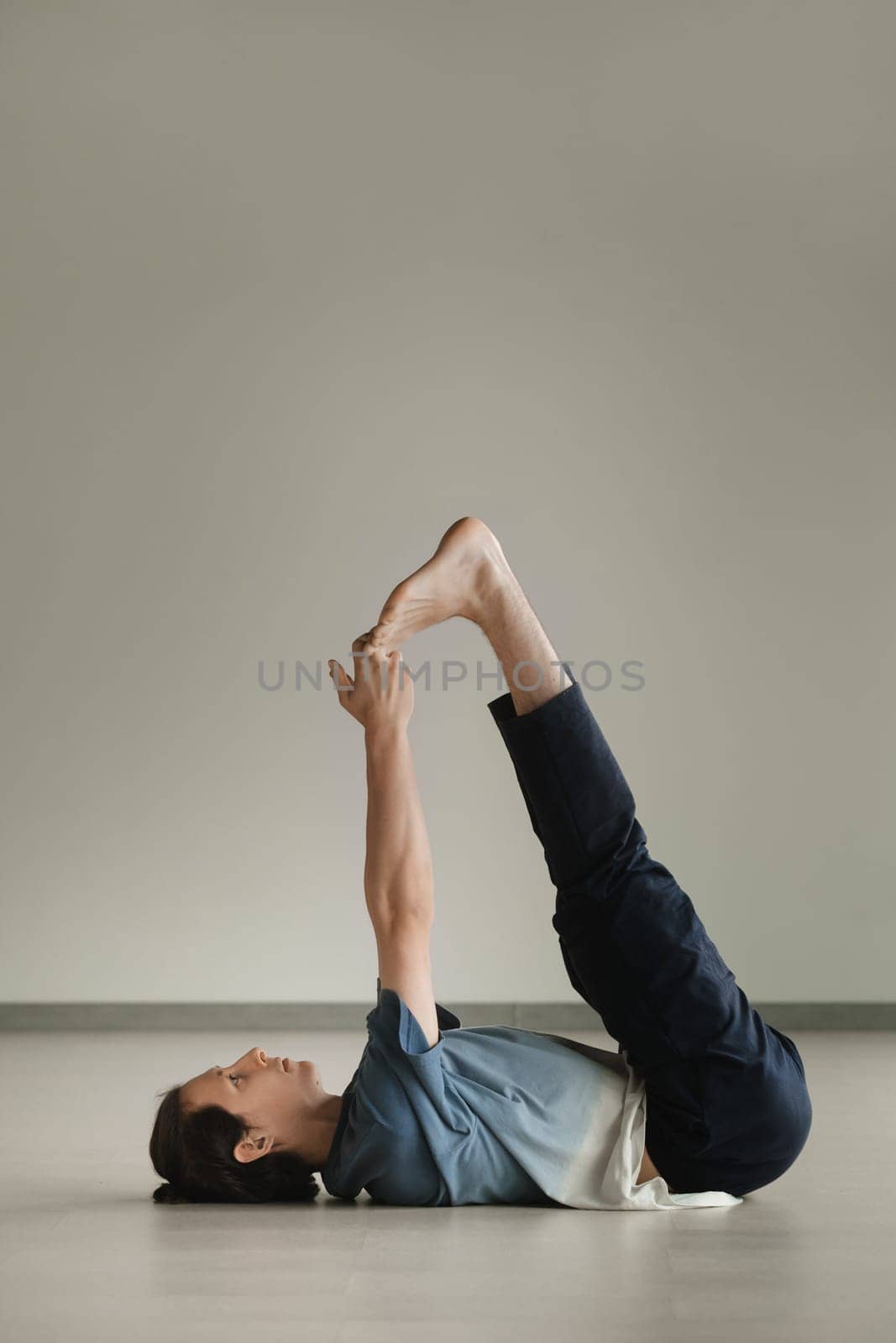 a man in a sports uniform does yoga in a fitness room. the concept of a healthy lifestyle by Lobachad