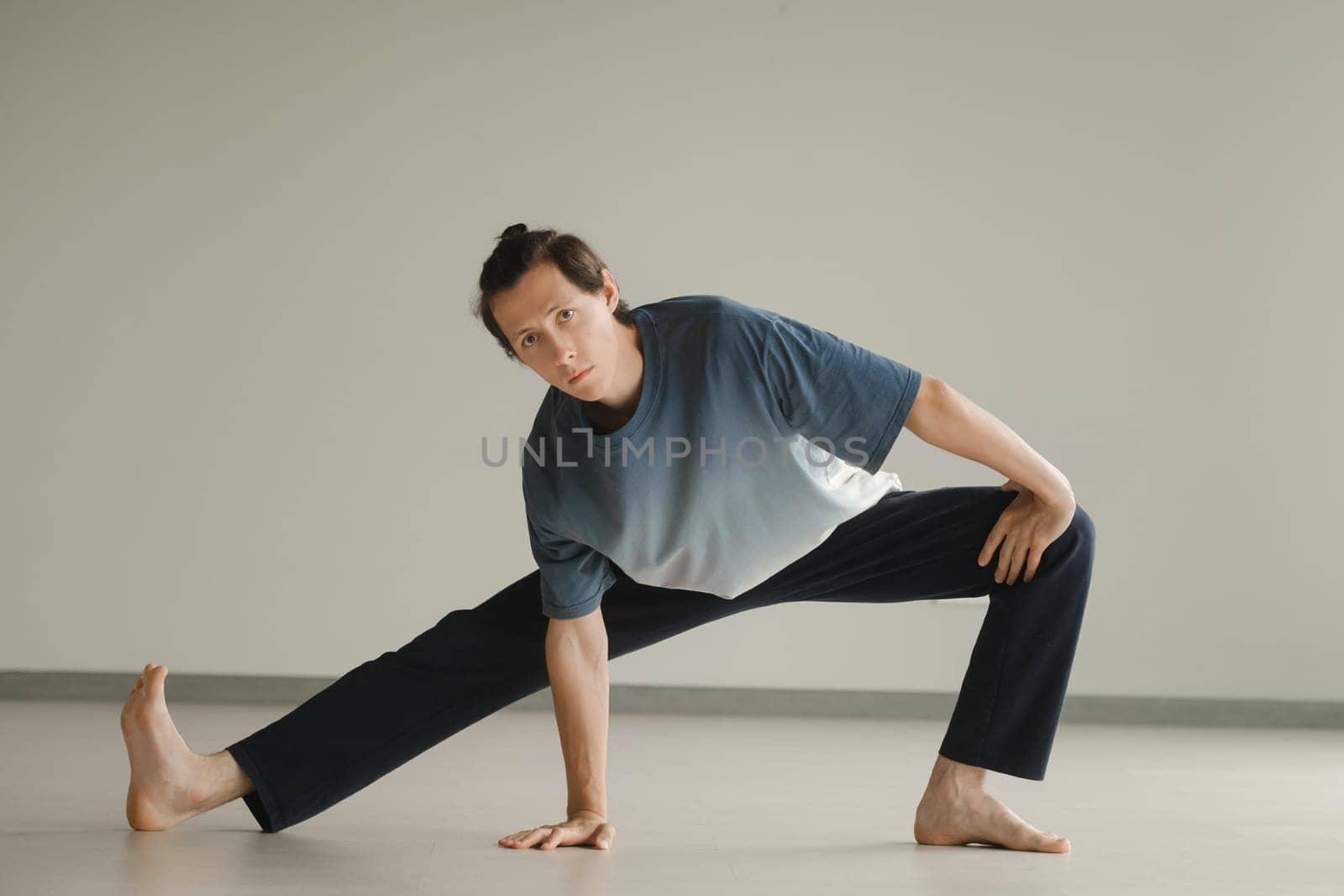 a man in a sports uniform does yoga in a fitness room. the concept of a healthy lifestyle by Lobachad