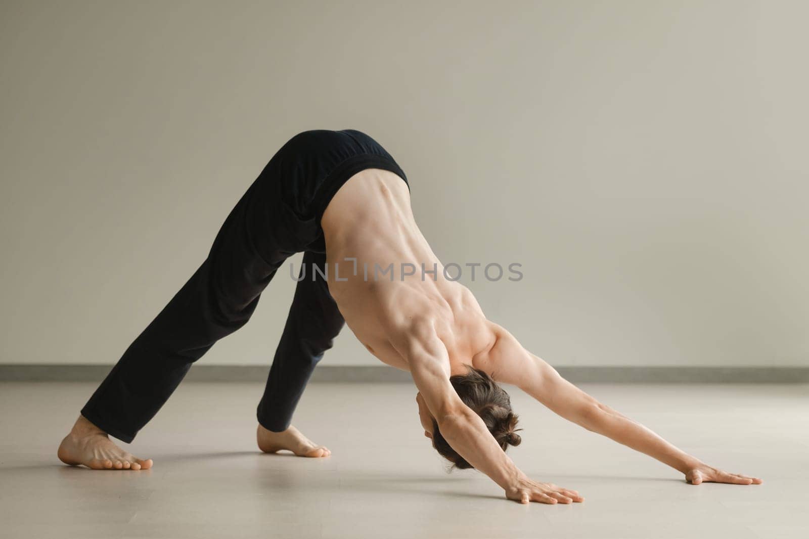 a man with a naked torso does yoga in the gym. the concept of a healthy lifestyle by Lobachad