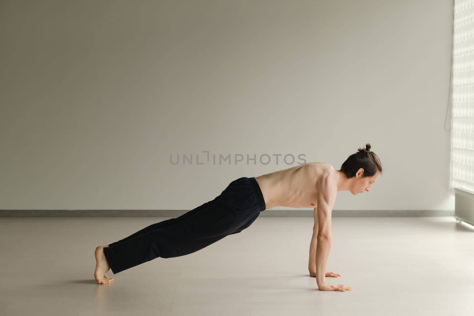 a man with a naked torso does yoga in the gym. the concept of a healthy lifestyle by Lobachad