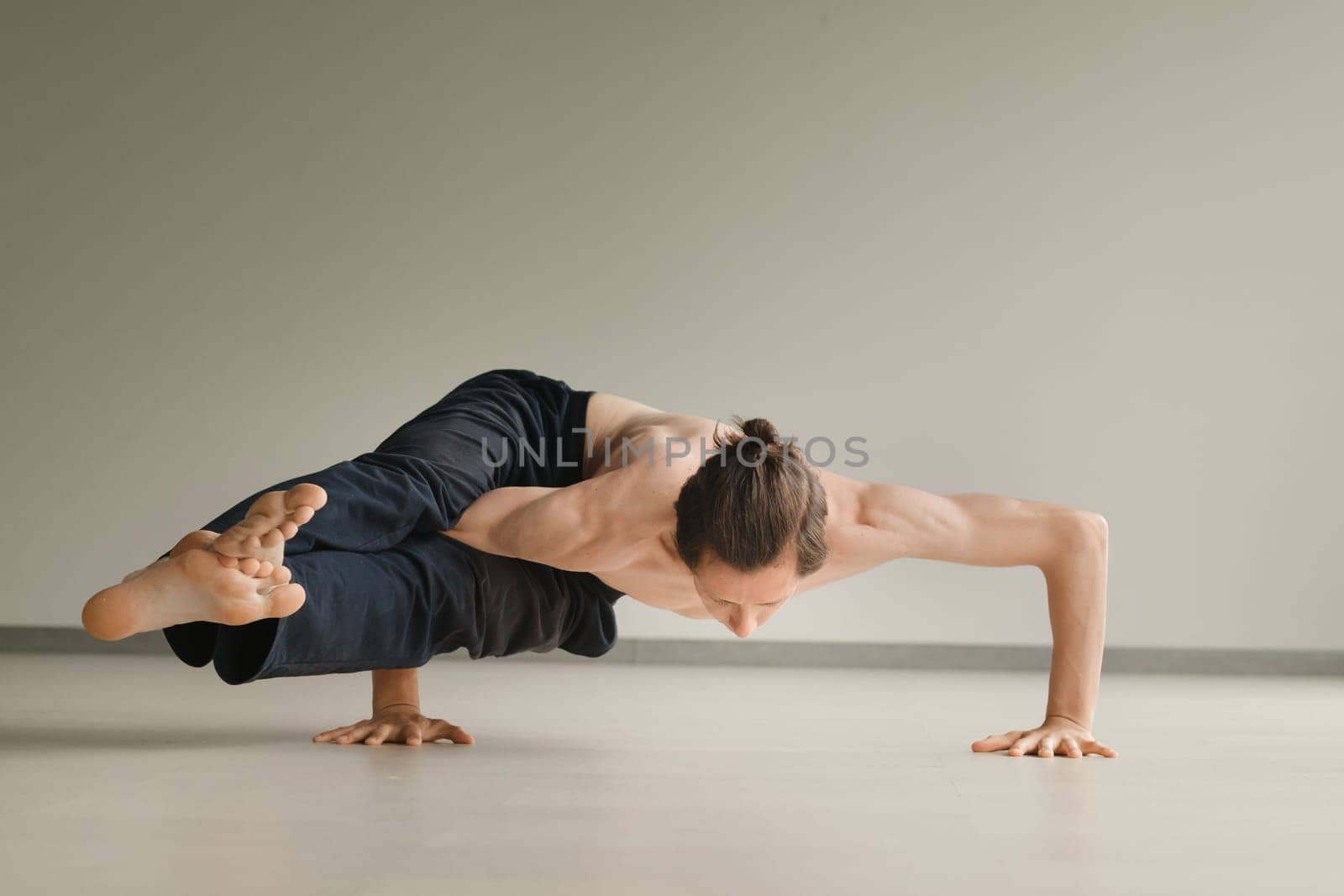 a man with a naked torso does yoga in the gym. the concept of a healthy lifestyle.