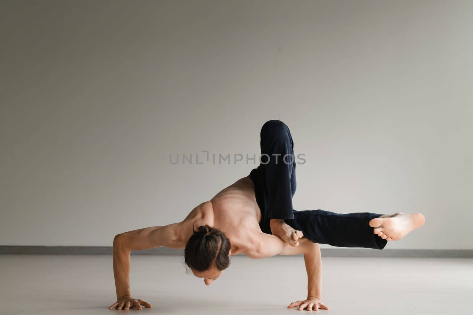 a man with a naked torso does yoga in the gym. the concept of a healthy lifestyle by Lobachad