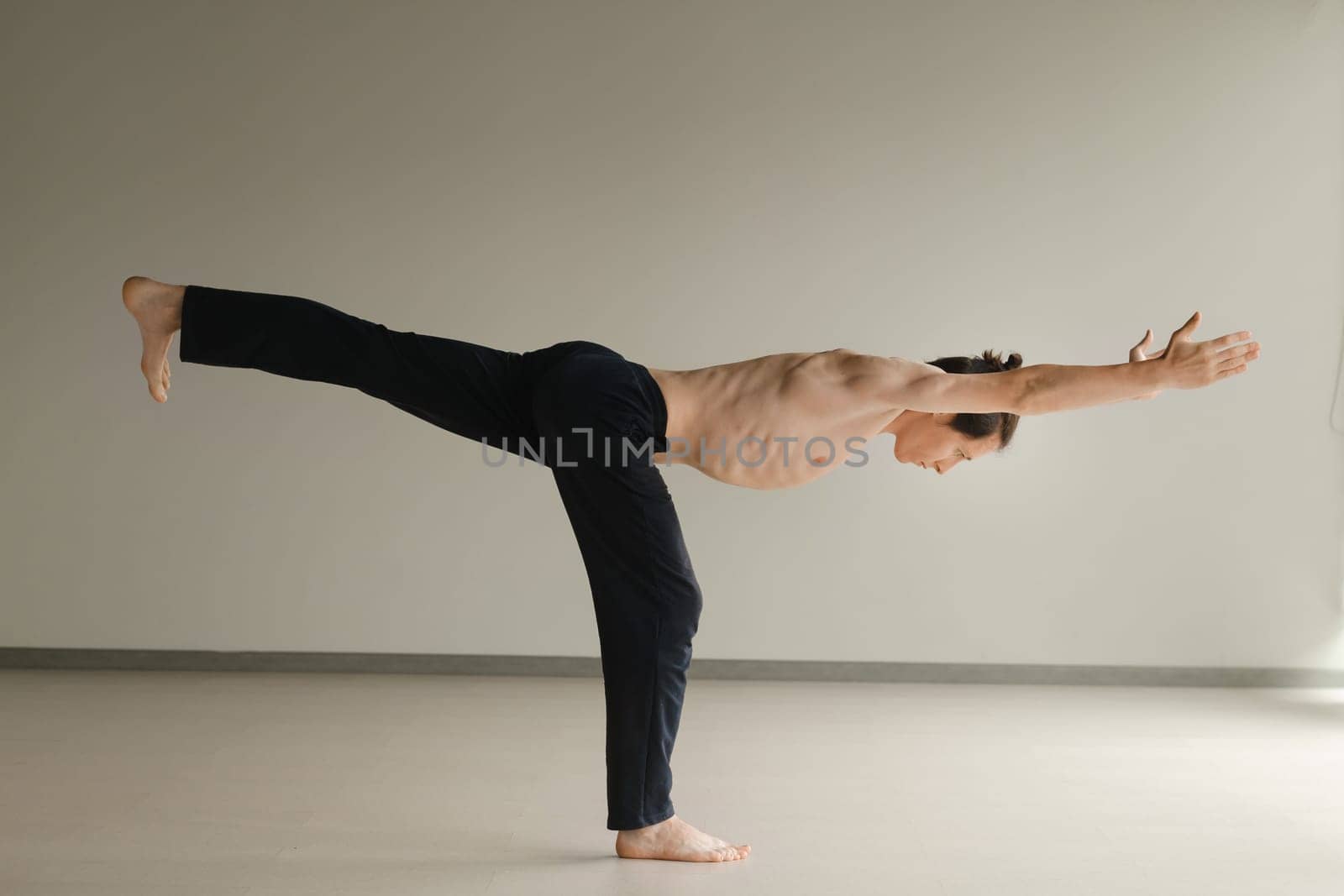 a man with a naked torso does yoga in the gym. the concept of a healthy lifestyle.