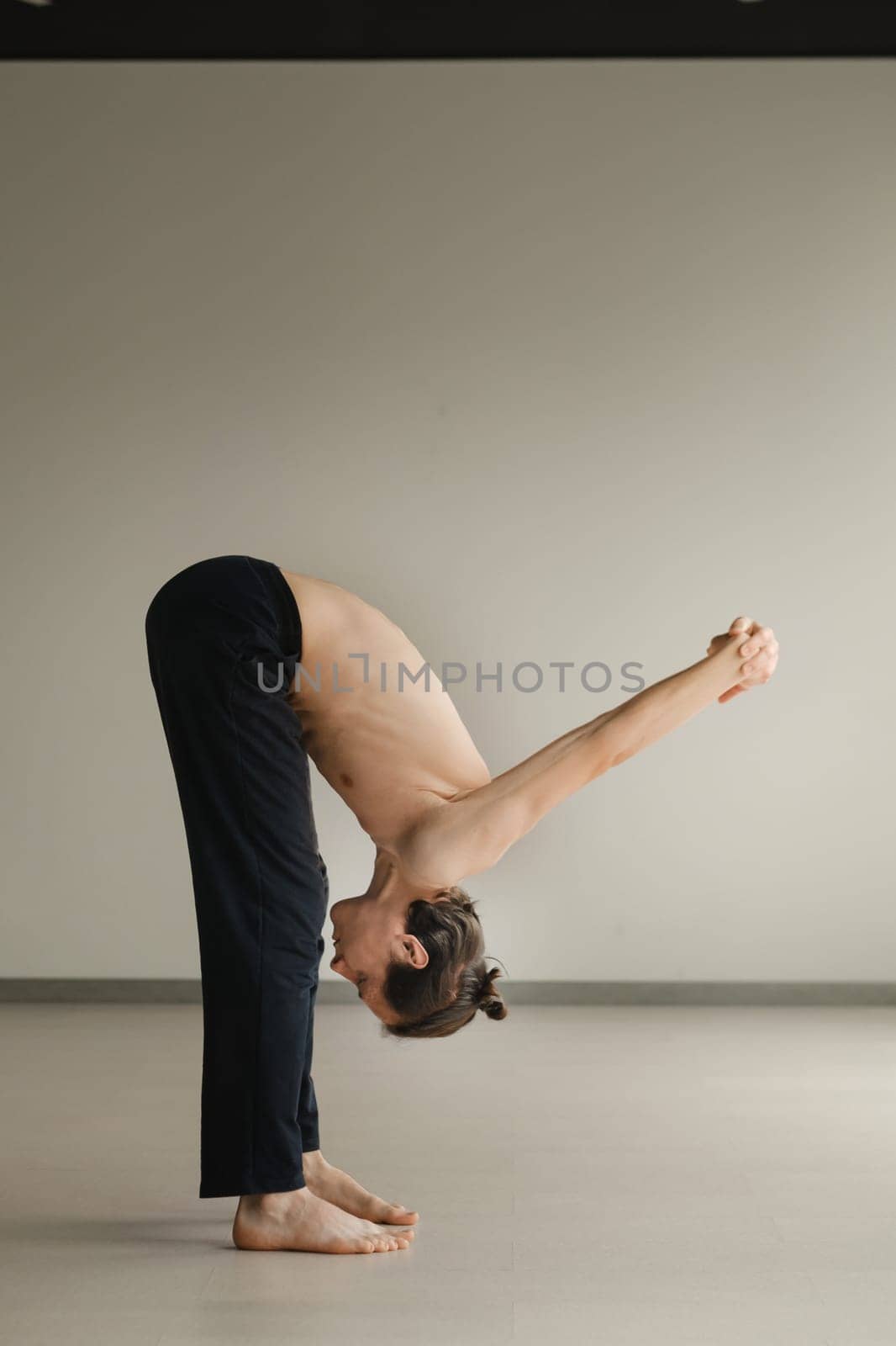 a man with a naked torso does yoga in the gym. the concept of a healthy lifestyle by Lobachad