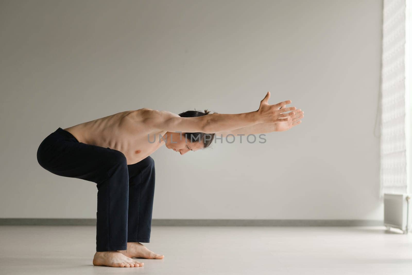 a man with a naked torso does yoga in the gym. the concept of a healthy lifestyle by Lobachad