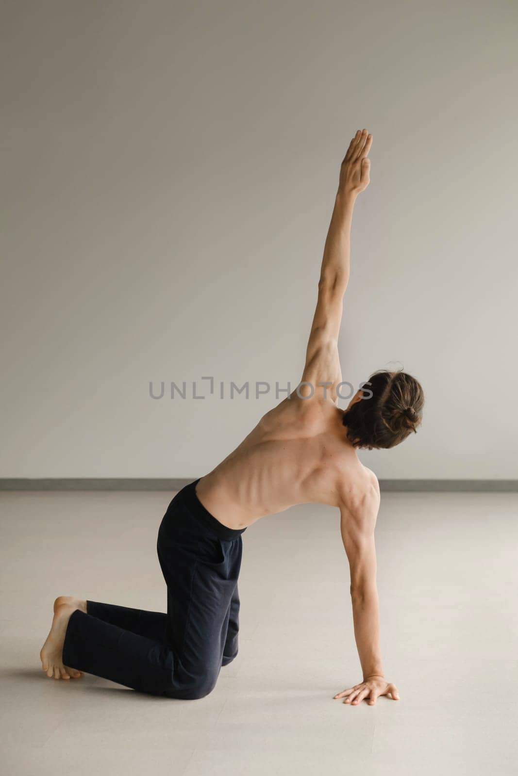 a man with a naked torso does yoga in the gym. the concept of a healthy lifestyle.