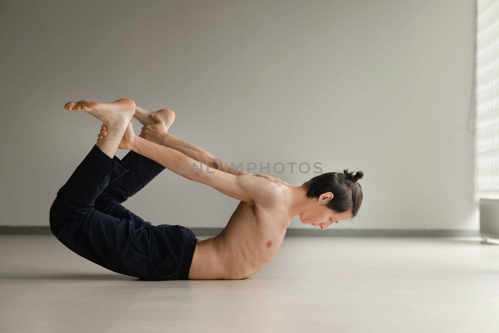 a man with a naked torso does yoga in the gym. the concept of a healthy lifestyle.