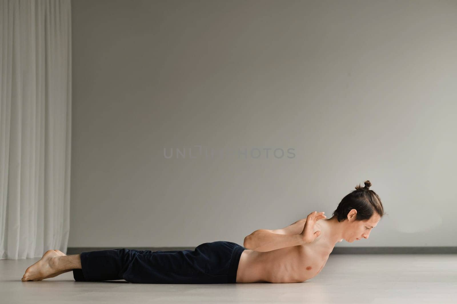 a man with a naked torso does yoga in the gym. the concept of a healthy lifestyle by Lobachad