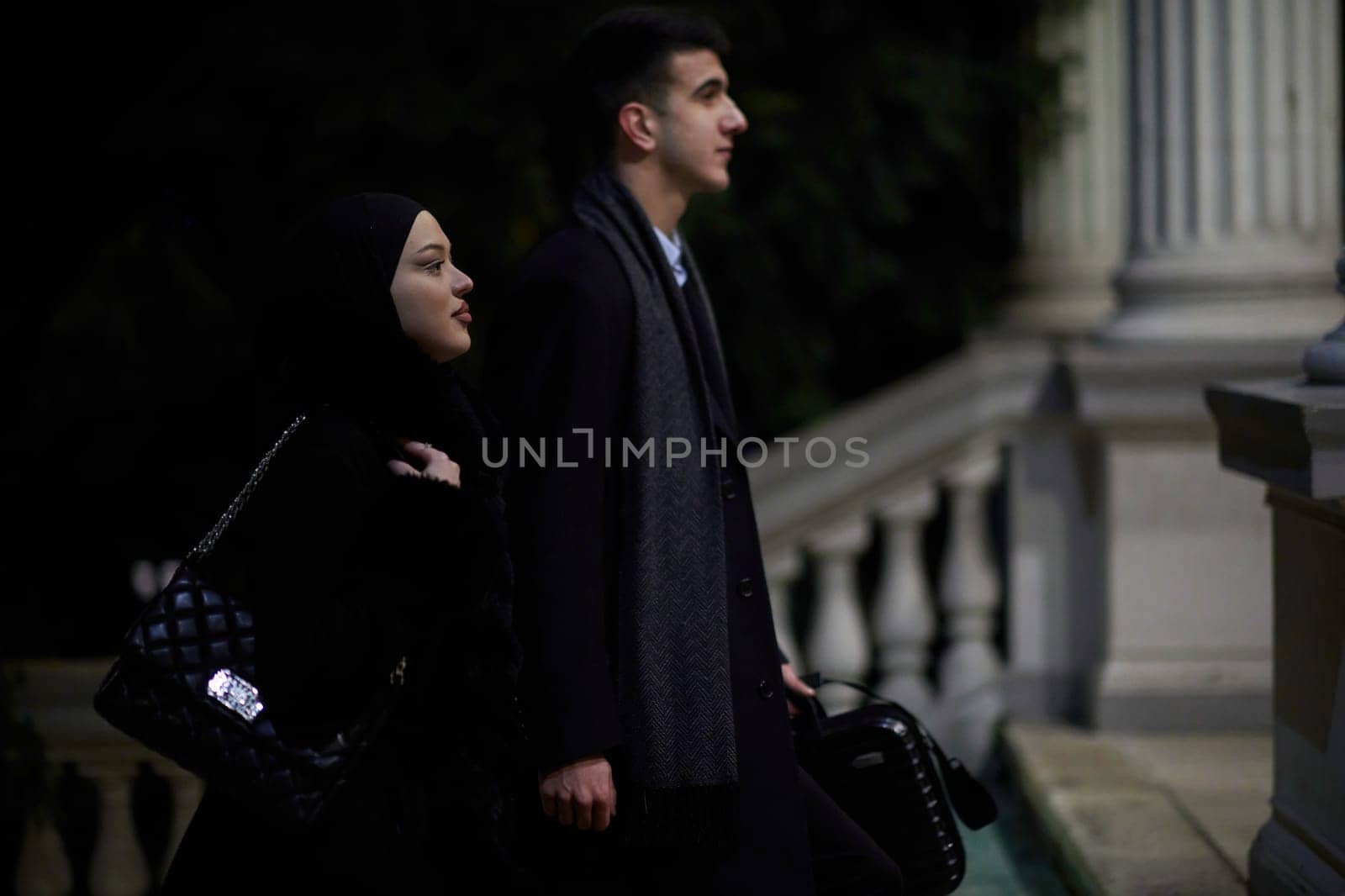 Happy multicultural business couple walking together outdoors in an urban city street at night near a jewelry shopping store window. by dotshock