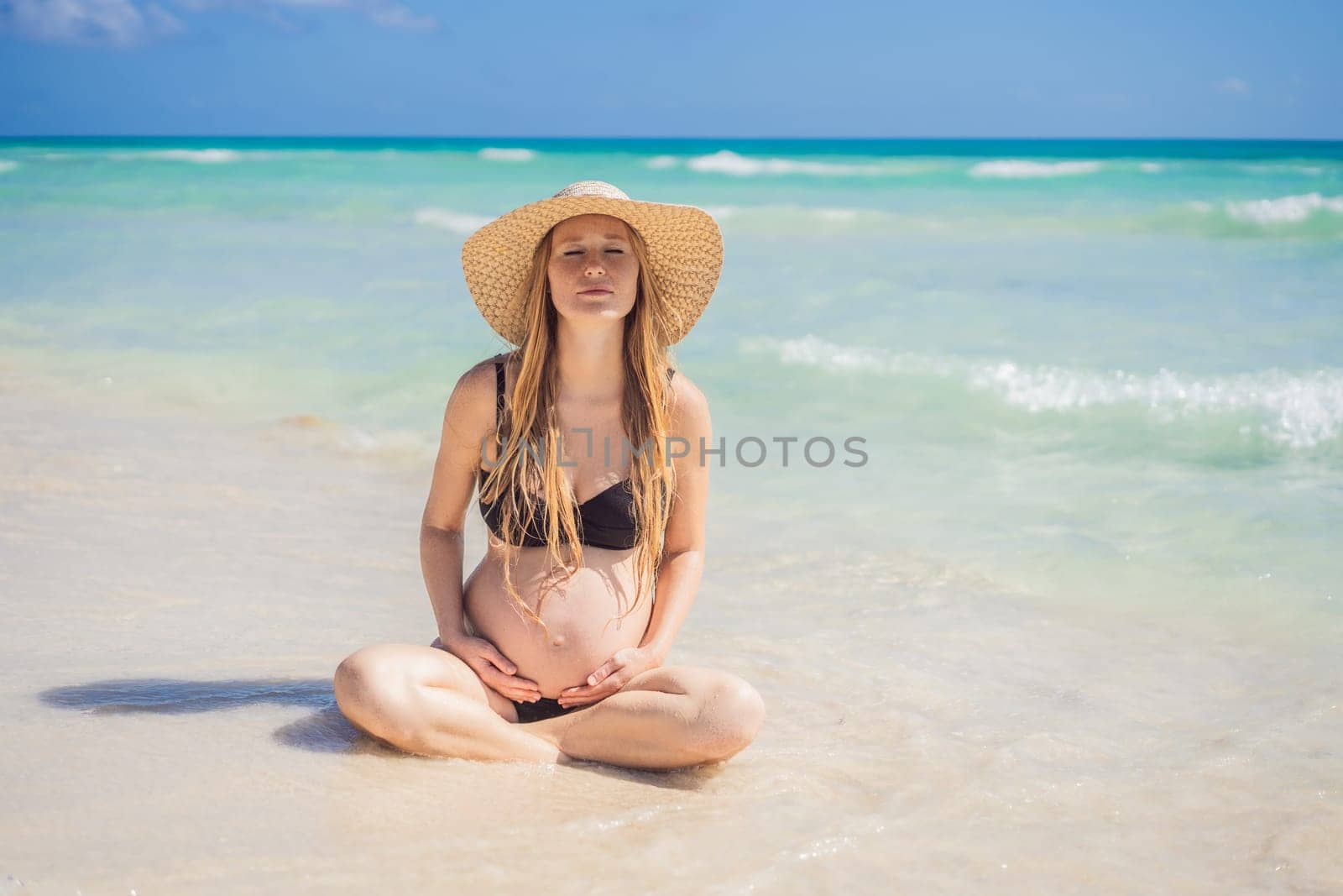 Radiant and expecting, a pregnant woman stands on a pristine snow-white tropical beach, celebrating the miracle of life against a backdrop of natural beauty.