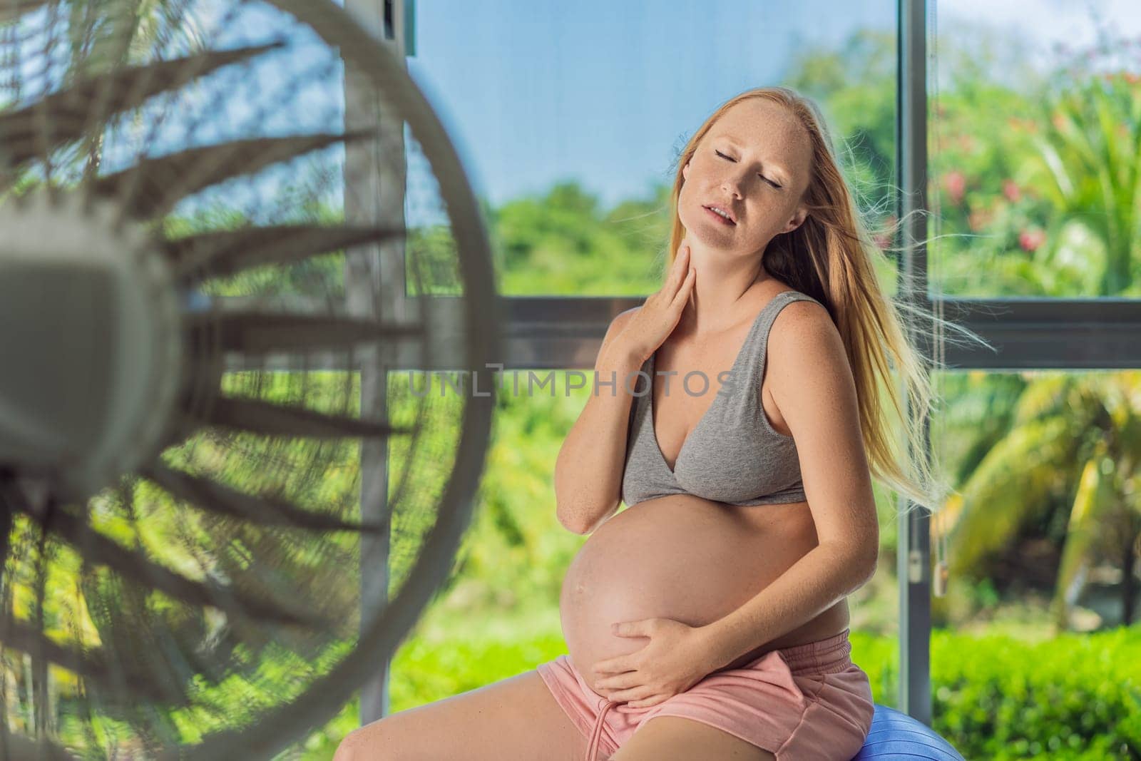 A pregnant woman seeks relief from an abnormal heatwave by using a fan, ensuring her comfort and well-being during sweltering conditions.