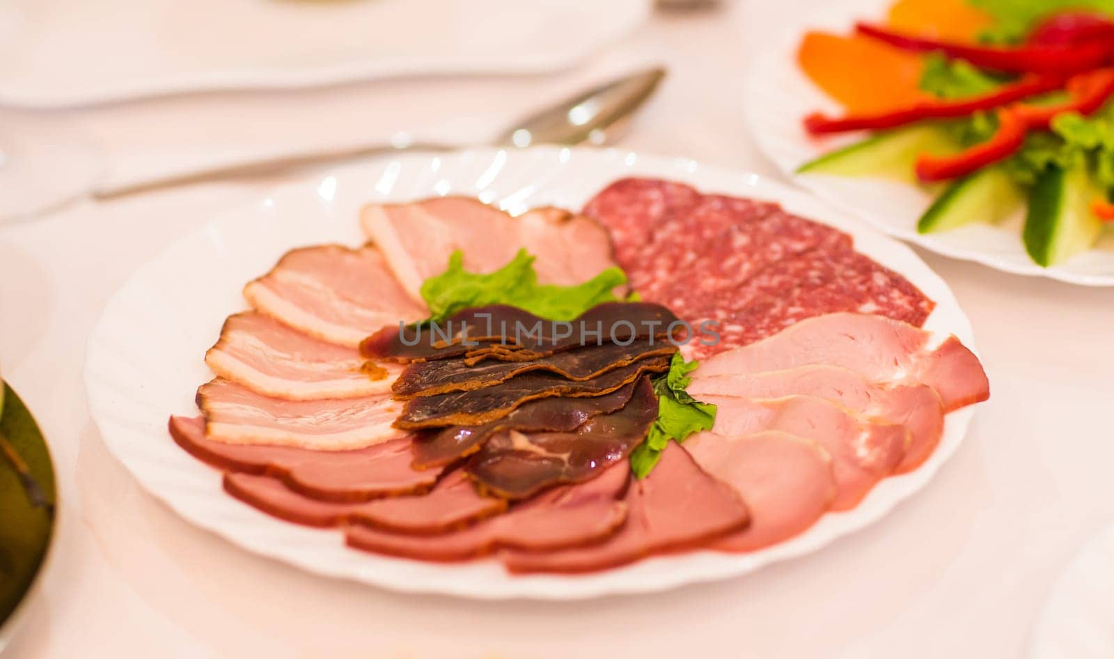 platter of sliced ham,salami and cured meat with vegetable decoration on festive table