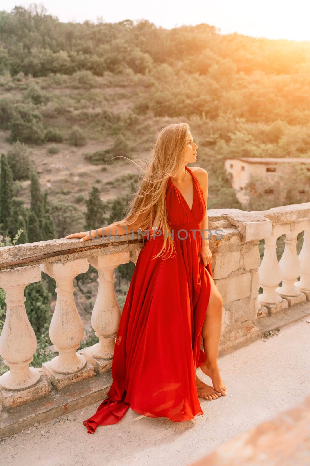 Woman red dress. Summer lifestyle of a happy woman posing near a fence with balusters over the sea