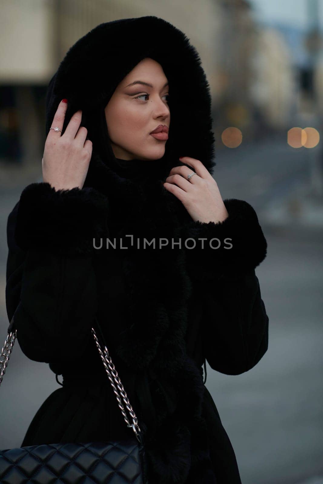 Muslim woman walking on an urban city street on a cold winter night wearing hijab by dotshock