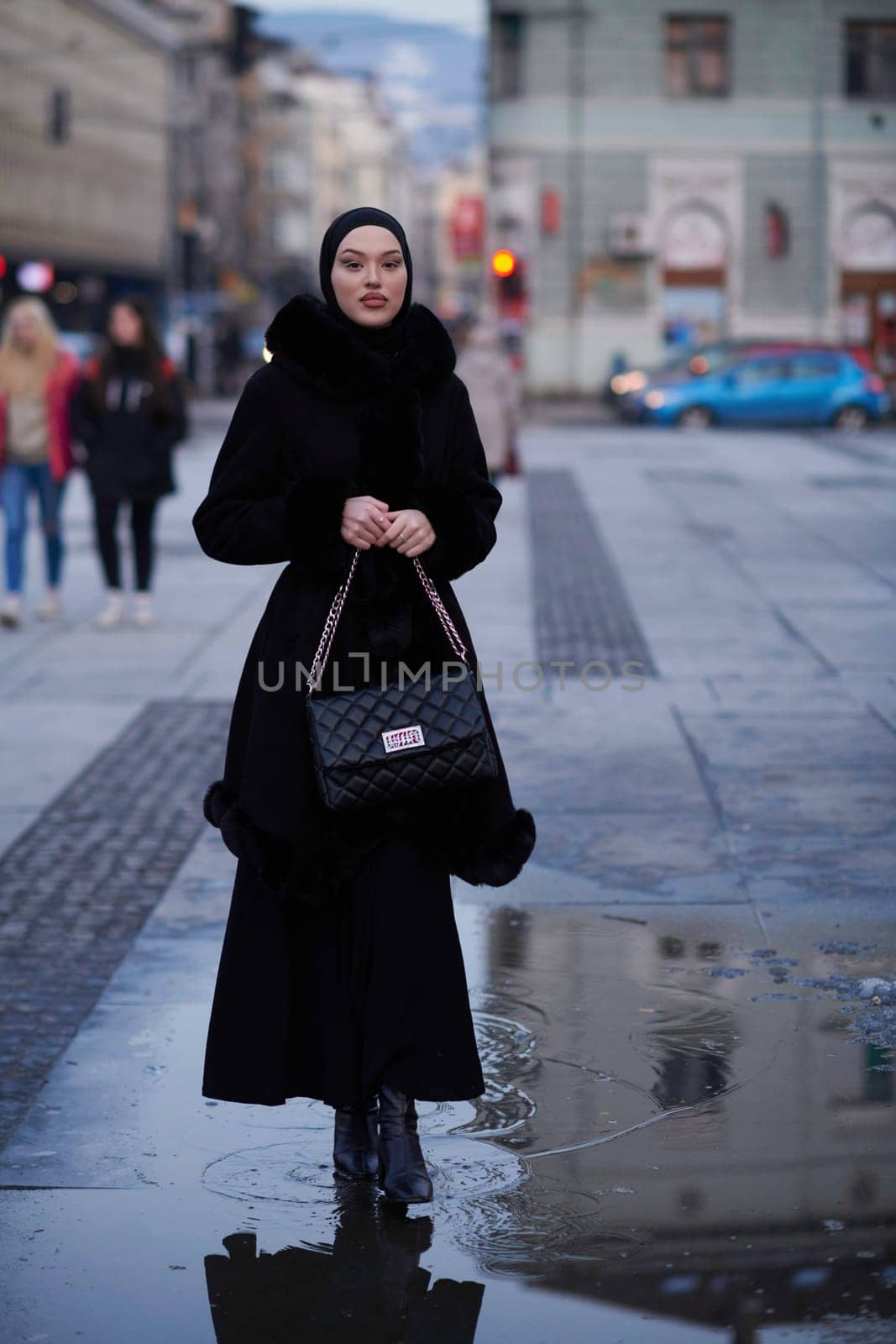 Muslim woman walking on an urban city street on a cold winter night wearing hijab by dotshock