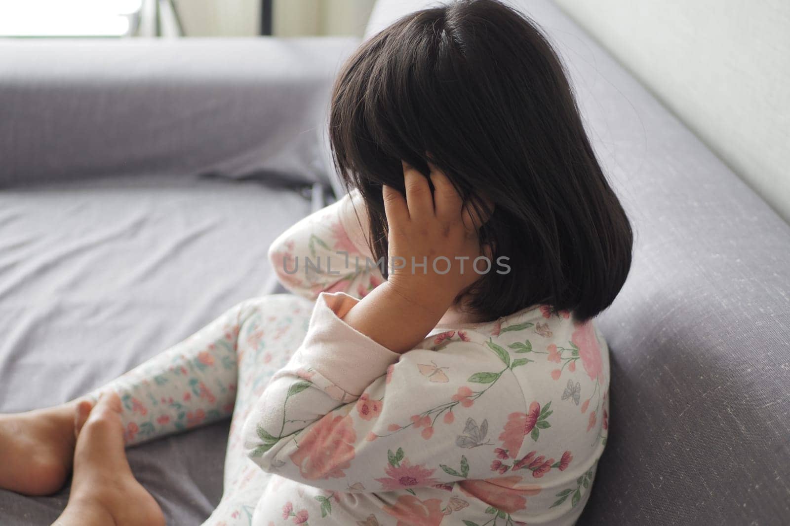 a upset child girl cover her face with hand sitting on sofa by towfiq007