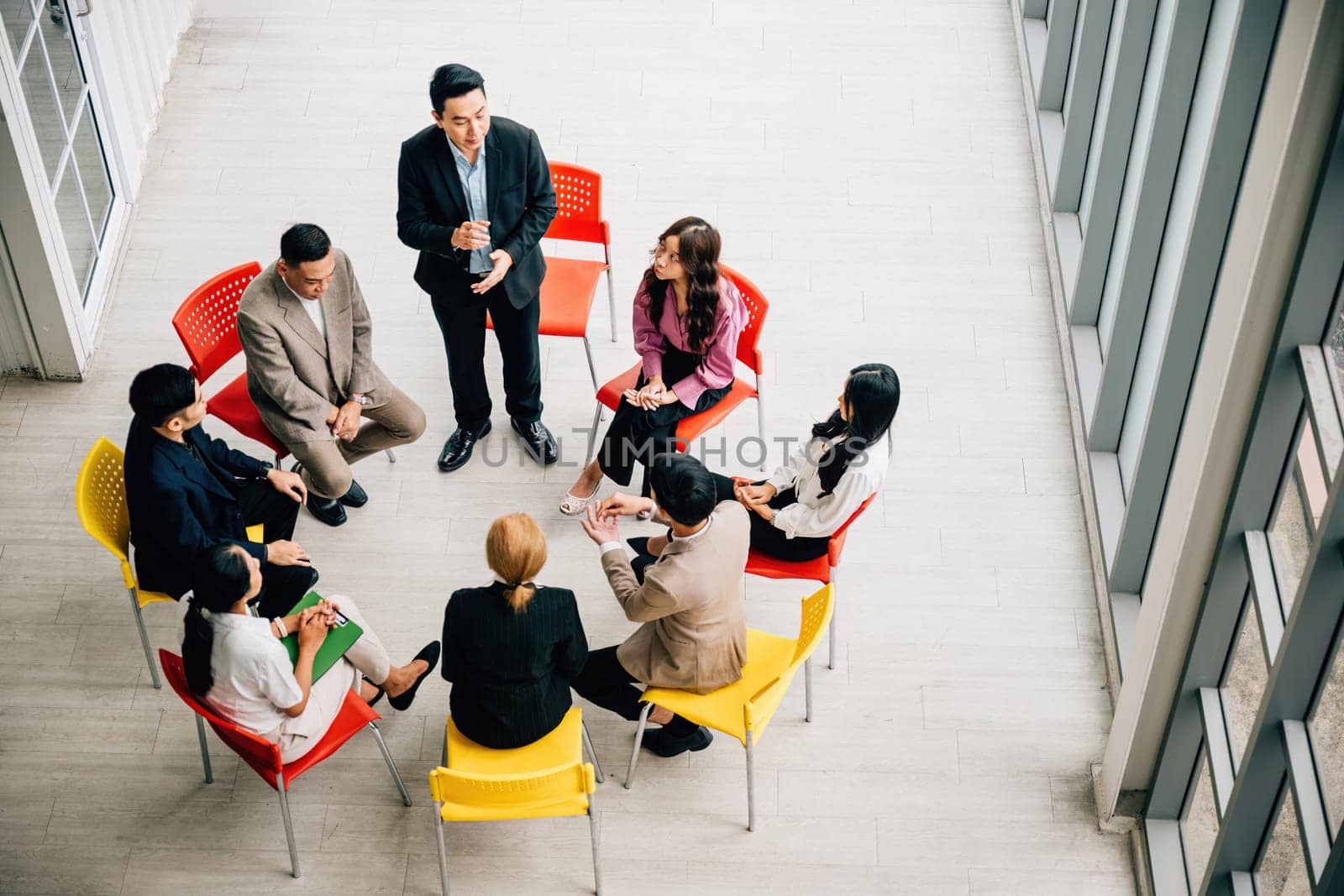 In an office, a top view captures diverse colleagues working together. A businesswoman and businessman sit around a conference table, creating an ideal backdrop for a successful meeting concept.