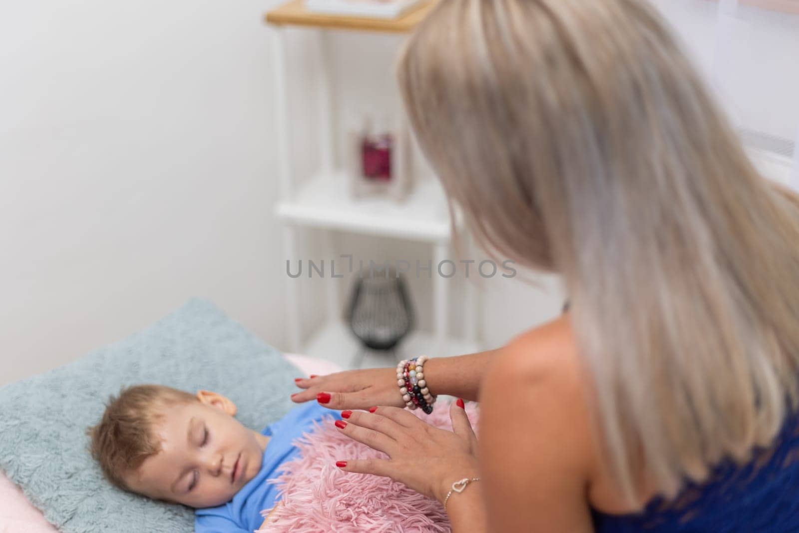Woman healer performing access or consciousness bars to young boy, a pseudoscientific method of alternative medicine that focuses on massaging various points on the head, alternative medicine concept