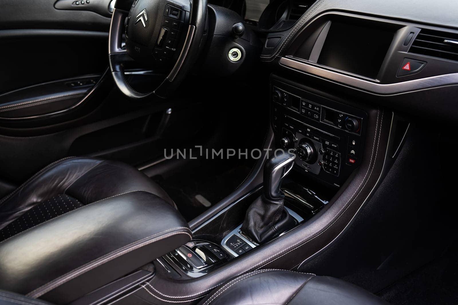 Modern car interior with a multimedia screen and many buttons. Citroen car, gearbox and steering wheel in the frame