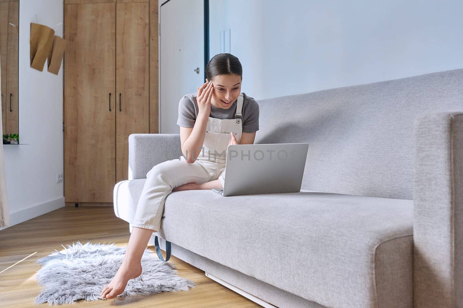 Teen girl at home on couch, emotional talking looking at laptop webcam, having video chat call conference. Technology for learning leisure communication, modern lifestyle, adolescence concept