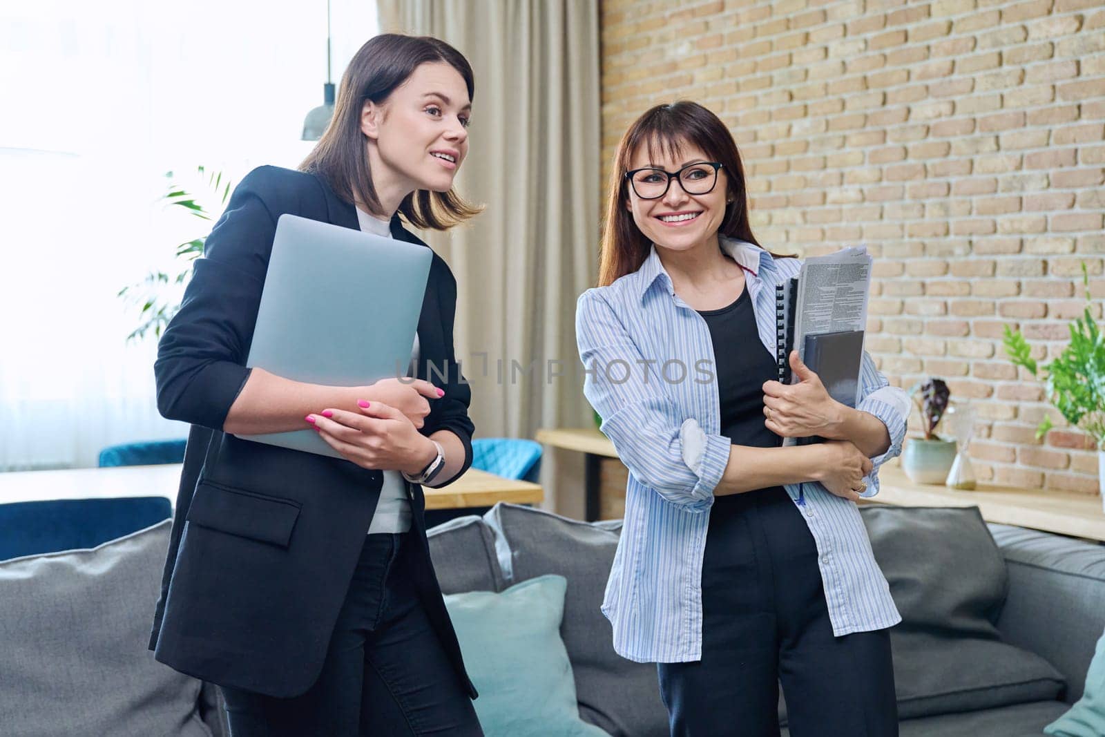 Two business women colleagues talking together in office by VH-studio