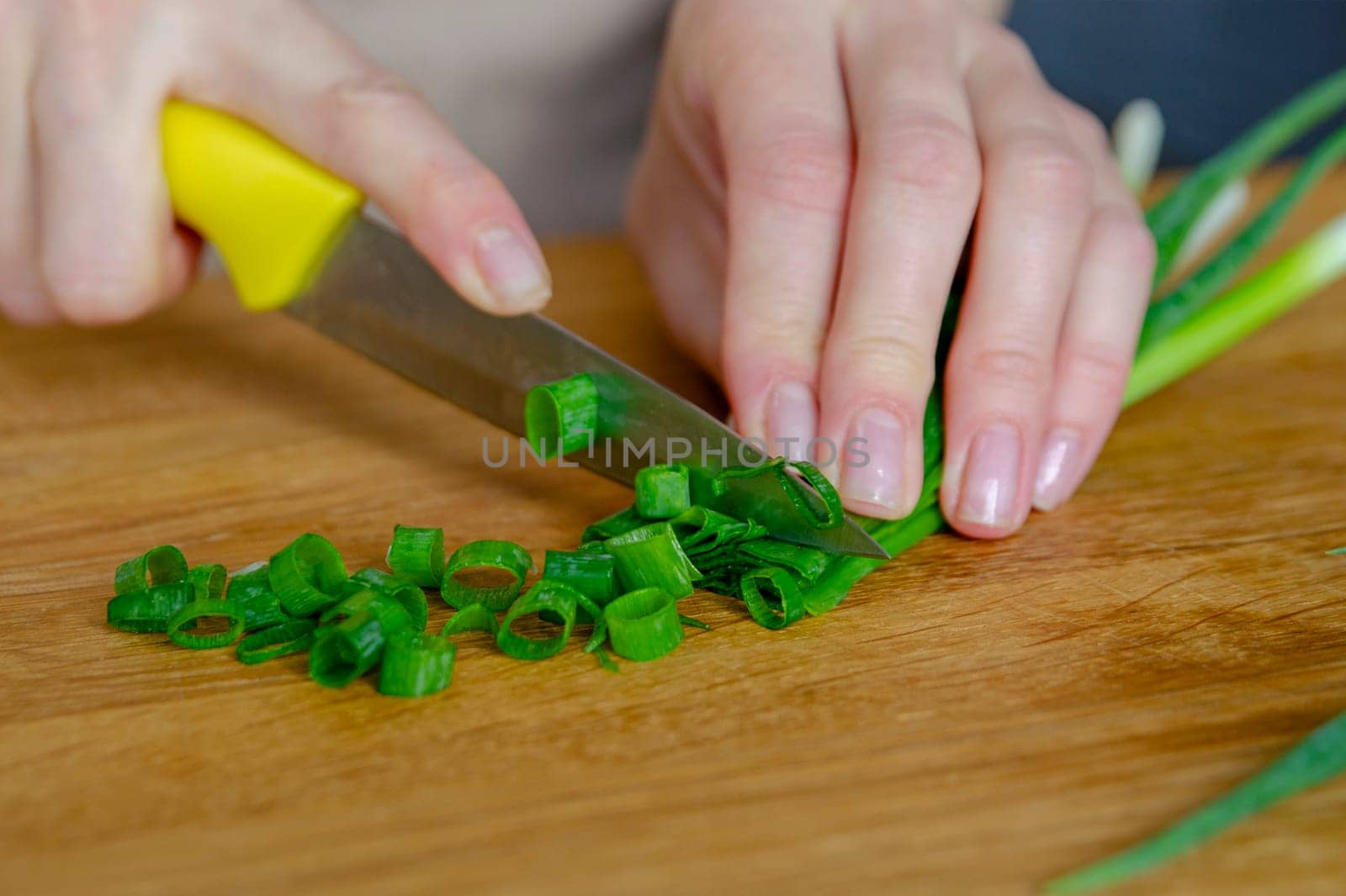 The process of preparing salad. A woman's hand chops a green onion close-up. Salad is used as a side dish for meals. High quality photo.