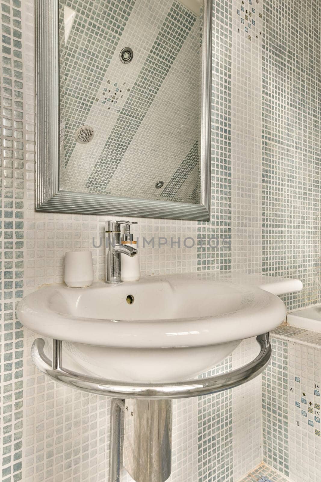 a white sink and mirror in a room with blue tiles on the wall behind it is an open shower stall