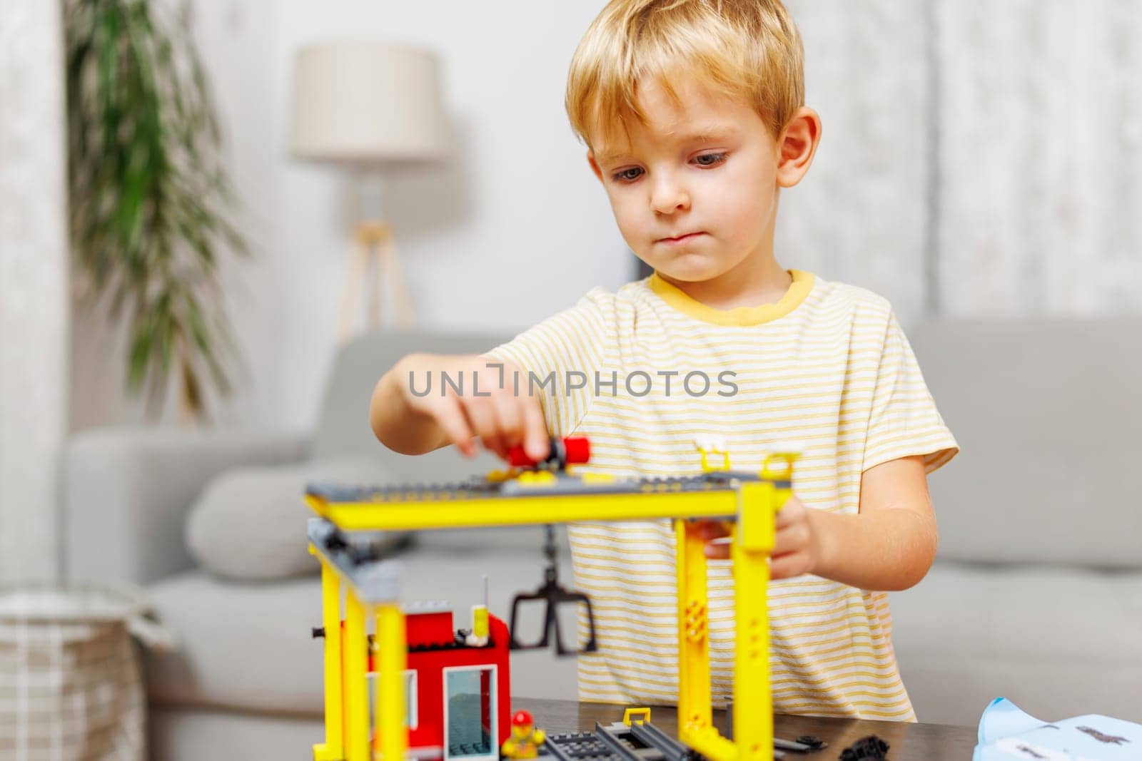 Child boy playing and building with colorful plastic bricks at the table. Early learning and development