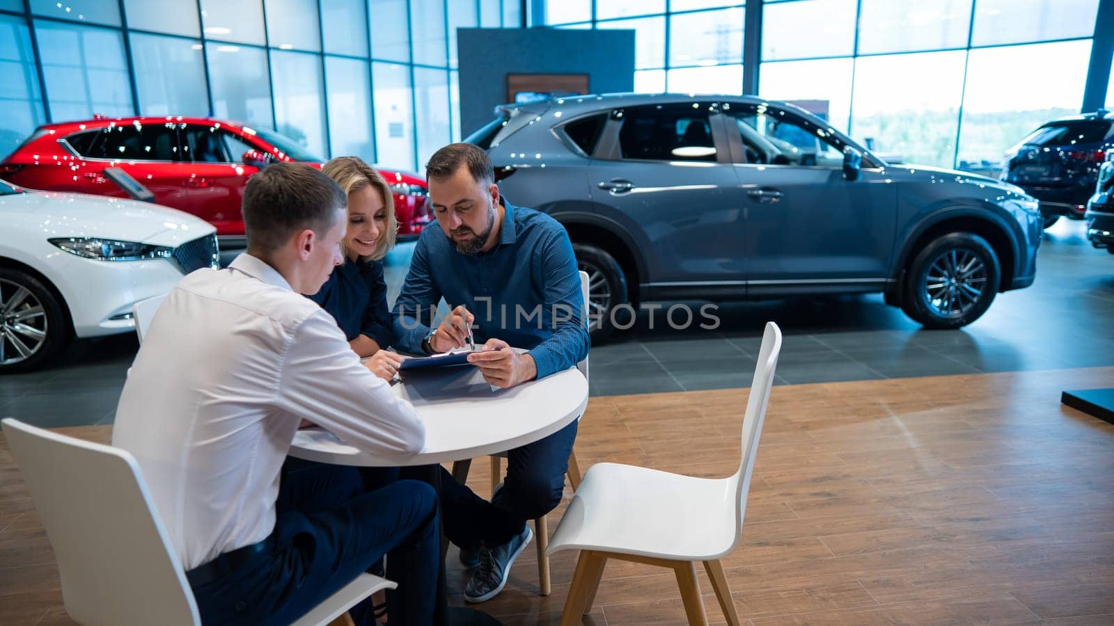 Happy caucasian couple signs a contract for the purchase of a car salon. by mrwed54