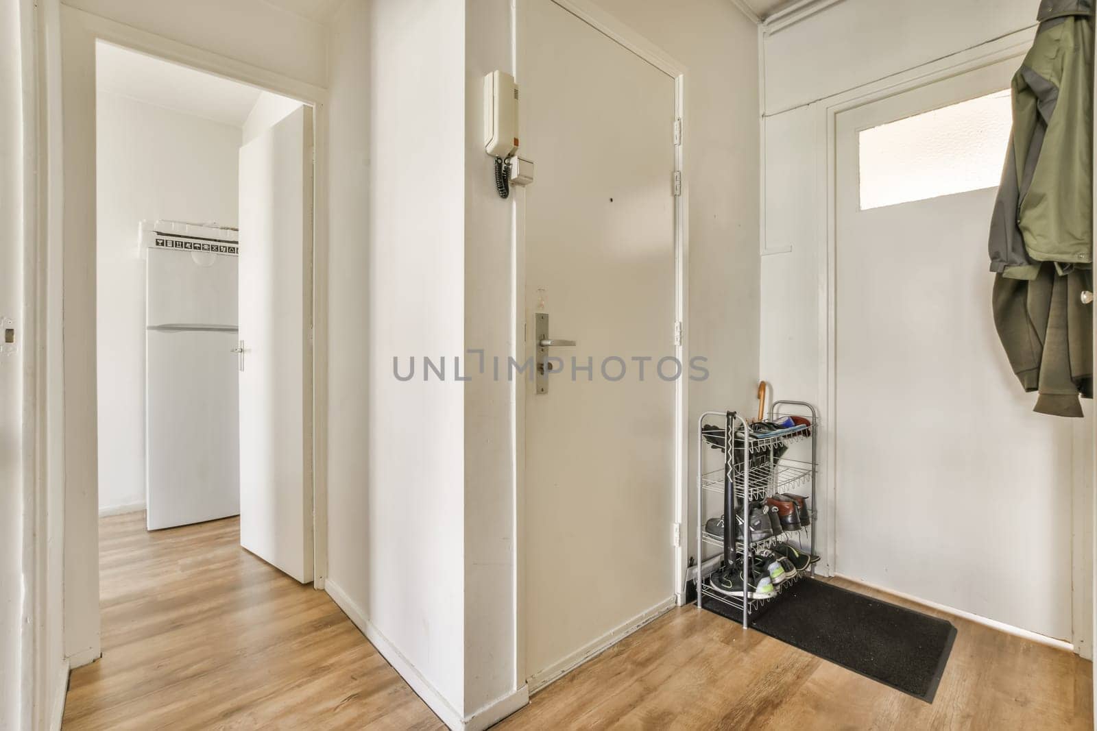 the inside of a room with wood floors and white walls, there is an open door that leads to another room