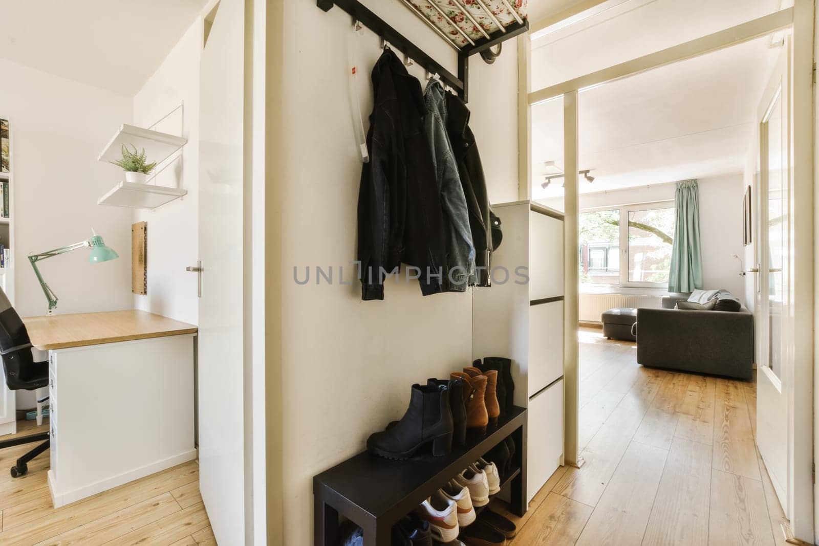 the inside of a house with wood flooring and clothes hanging on a coat rack in the door is open