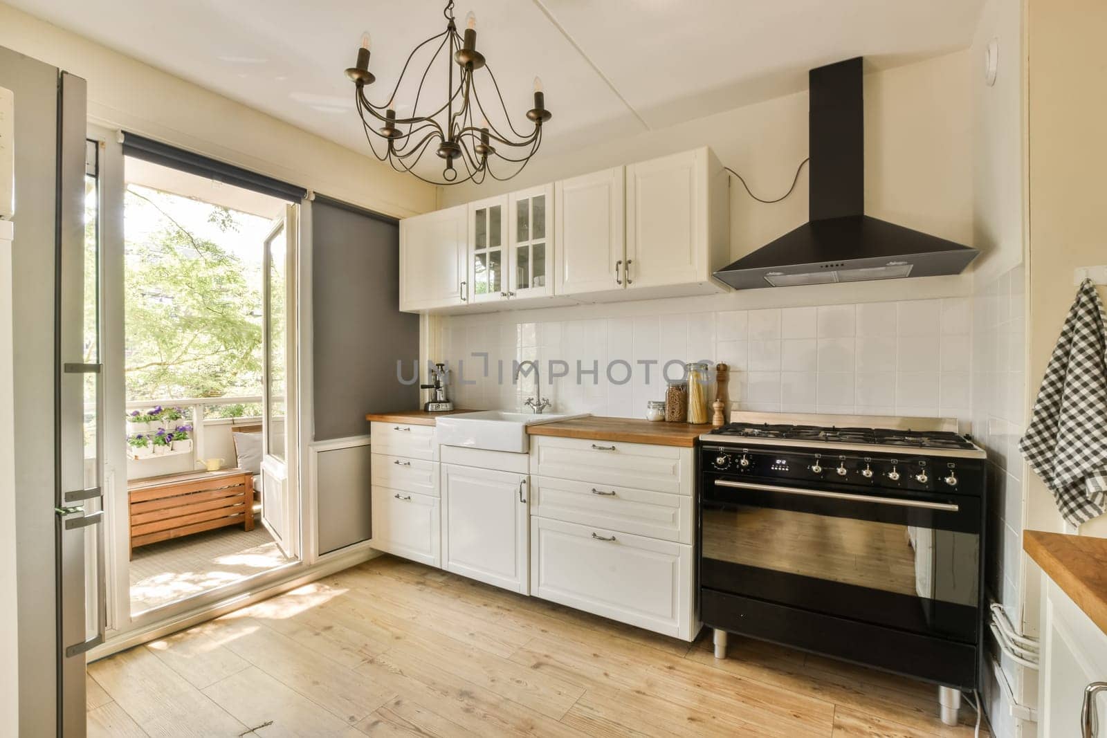 a kitchen with white cabinets and a black stove by casamedia