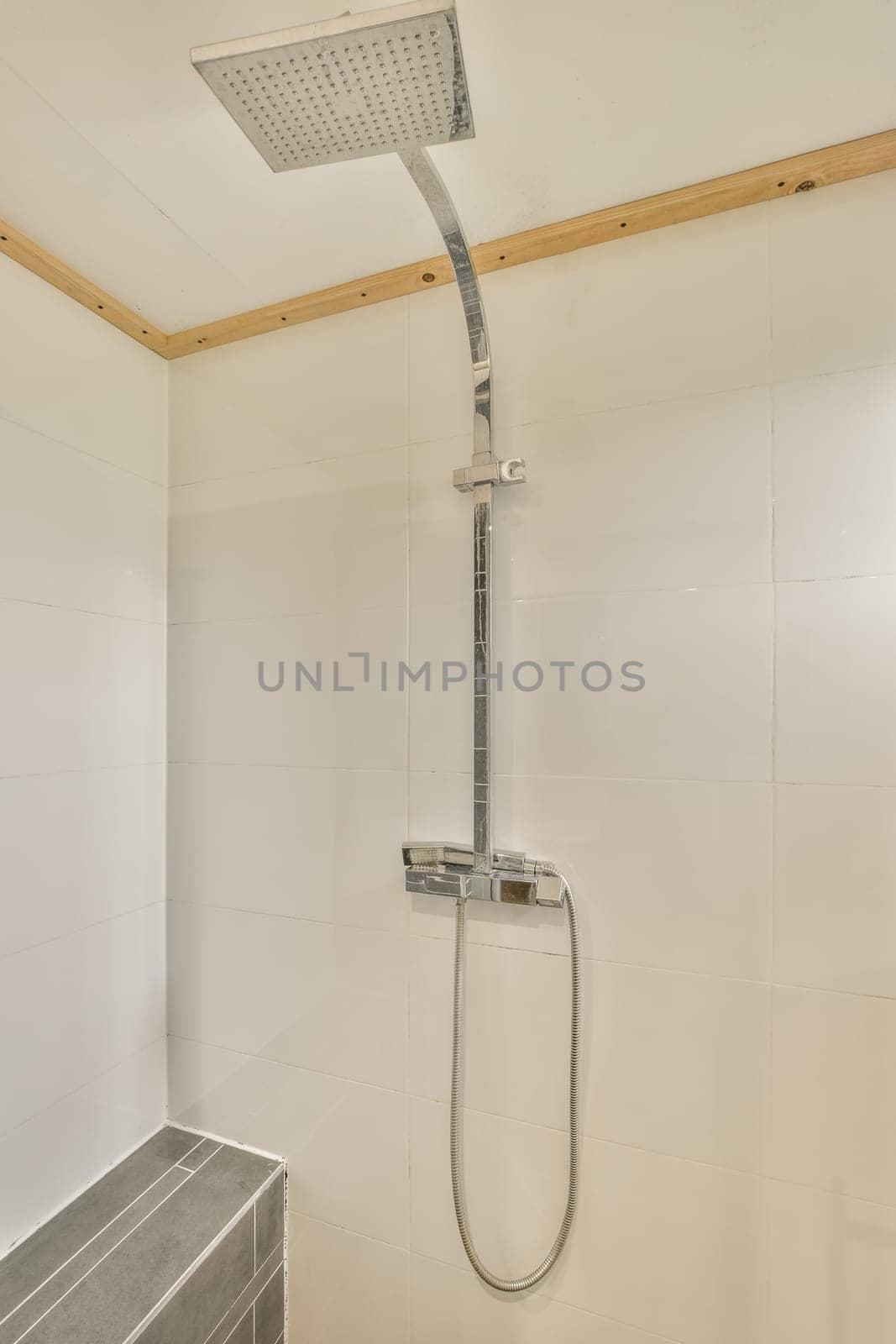 a modern bathroom with white tiles and wood trim on the walls, along with a shower head mounted to the wall