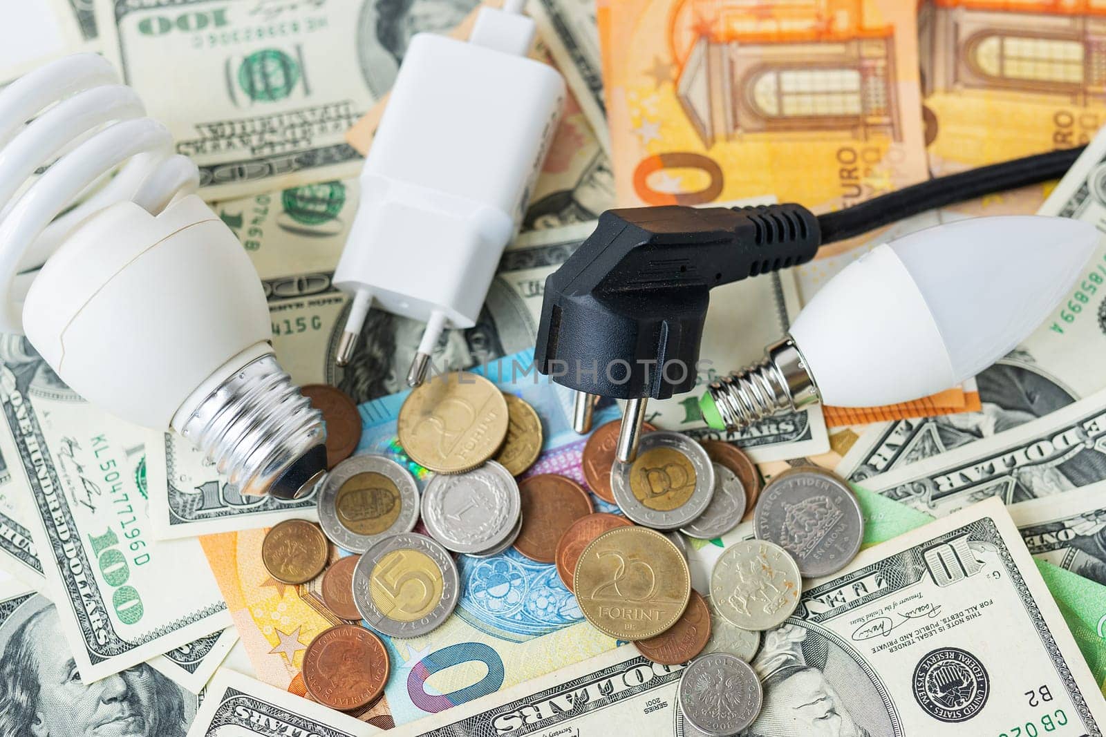 The concept of the energy crisis, price increases. Euro and dollar banknotes, coins on the background of a lamp, plug, cord. Tax time, bill payment, calculator for counting